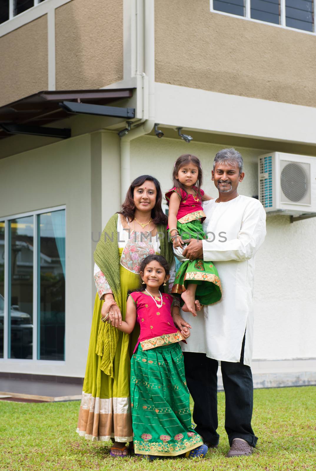 Beautiful Asian Indian family portrait smiling outside their new house.