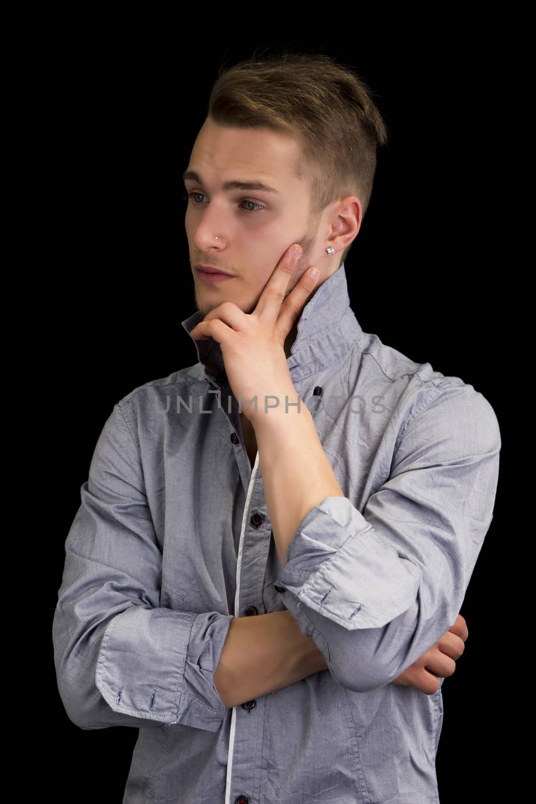 Attractive young man thinking, looking away with hand on his chin, on black background