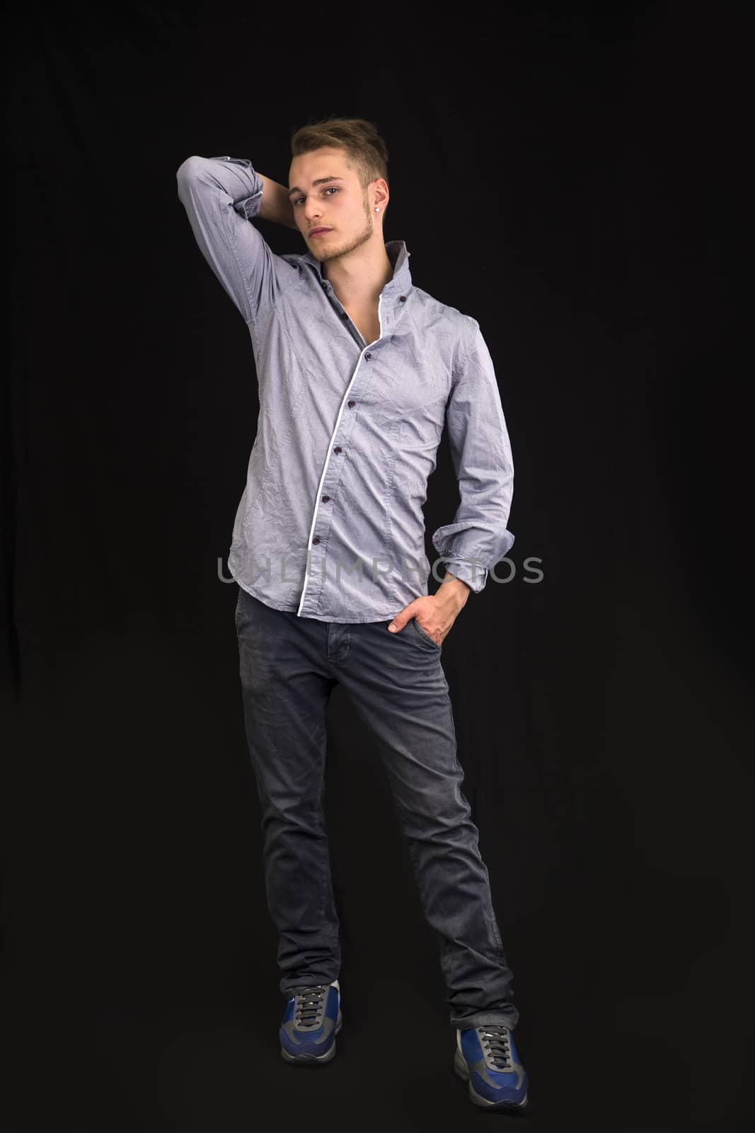 Full length portrait of handsome blond young man on dark background