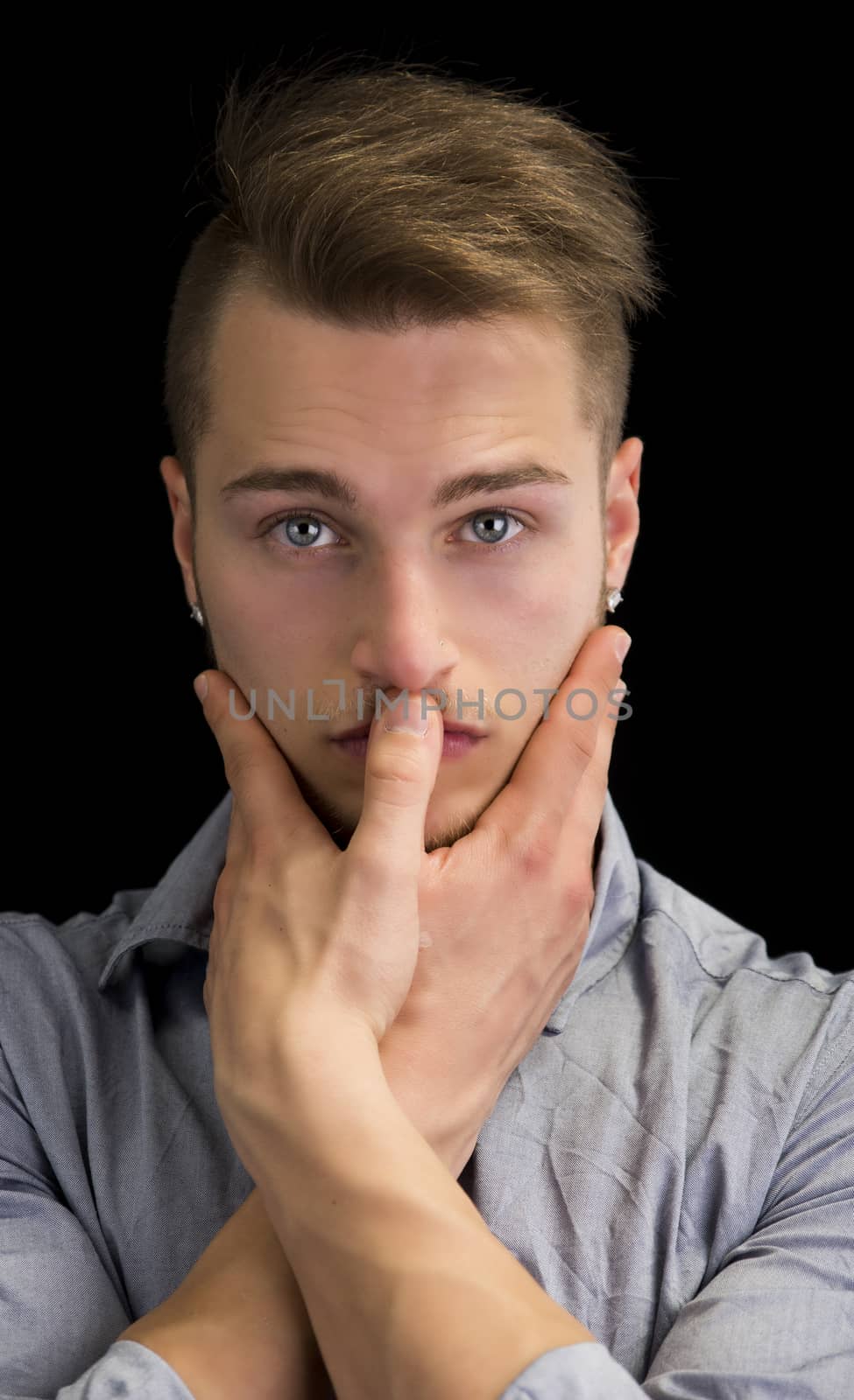 Attractive blond young man, serious expression with hands joined in front of mouth
