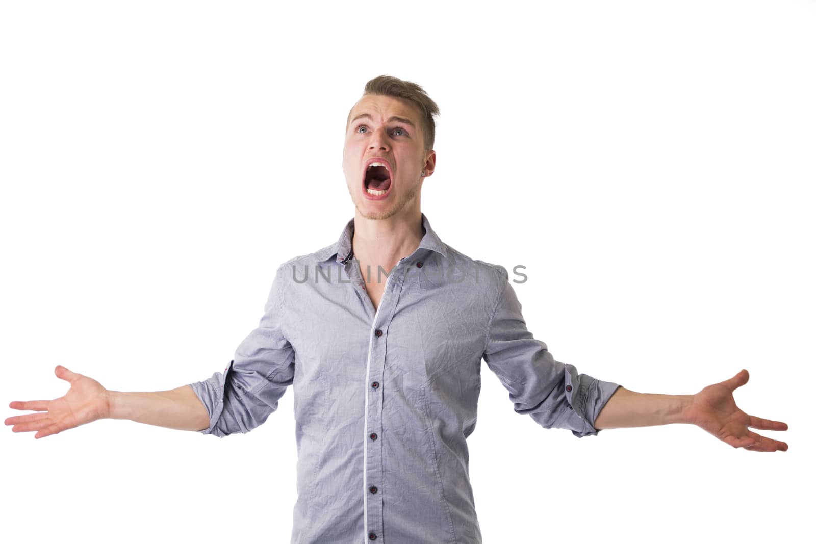 Desperate, angry young man screaming with arms open and looking up