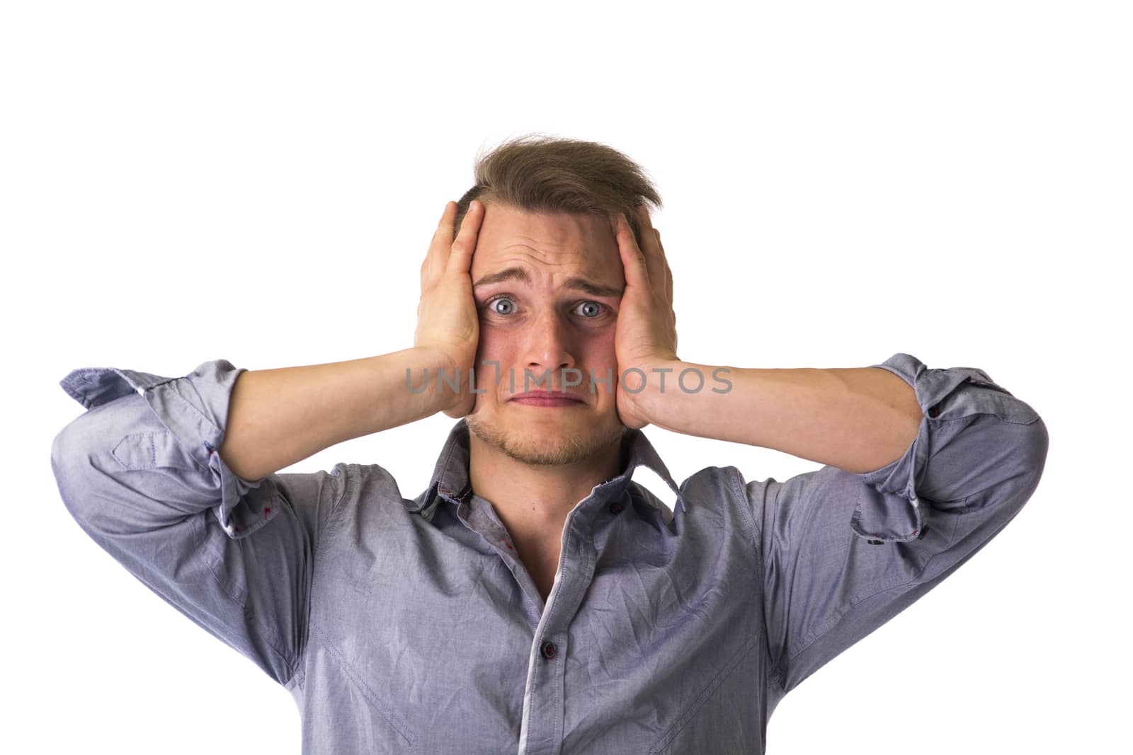 Desperate, upset young man with hands on his face and looking at camera