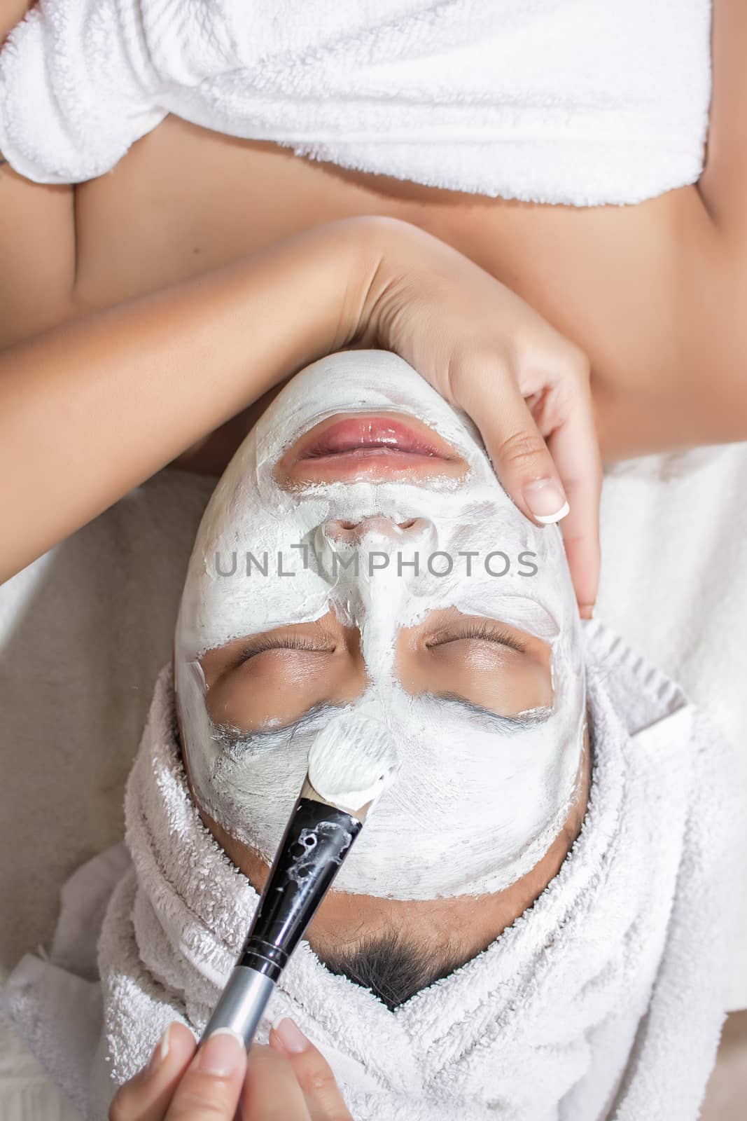 Woman having facial mask at beauty salon by castaldostudio