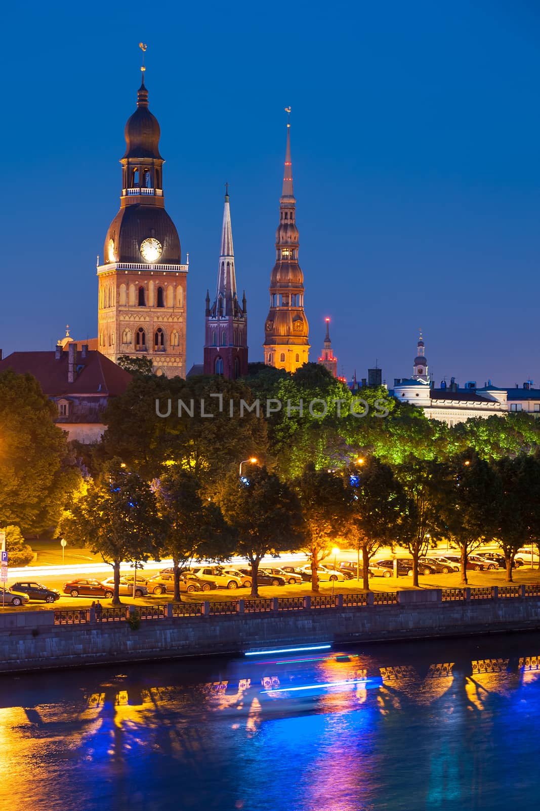 Towers of Riga seen across the river Daugava after the sunset. Three church towers in the picture are the Riga Dome cathedral,  St. Saviour's Church and St. Peter's church. On the right is Building of Academy of Sciences