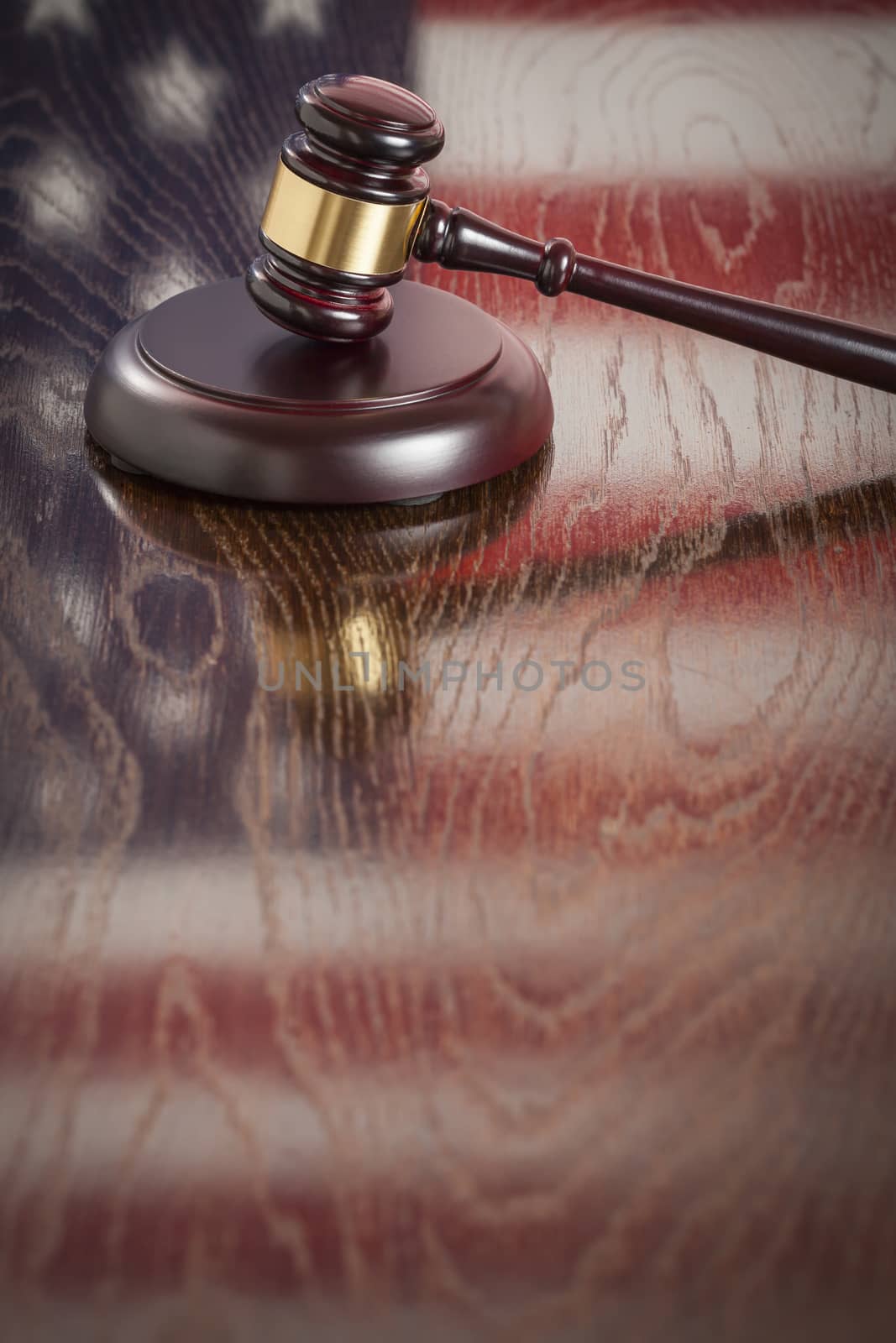 Wooden Gavel Resting on American Flag Reflecting Table.