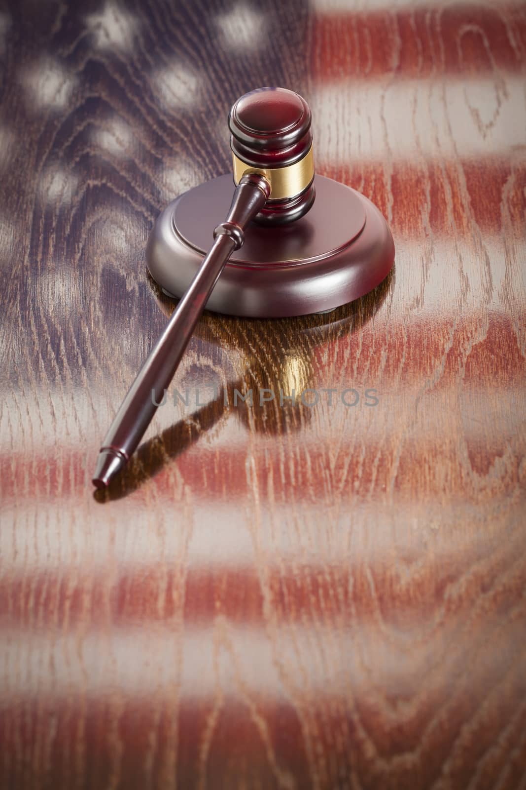 Wooden Gavel Resting on American Flag Reflecting Table.