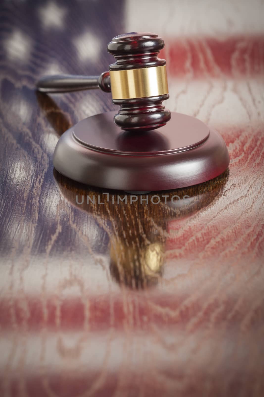 Wooden Gavel Resting on American Flag Reflecting Table.