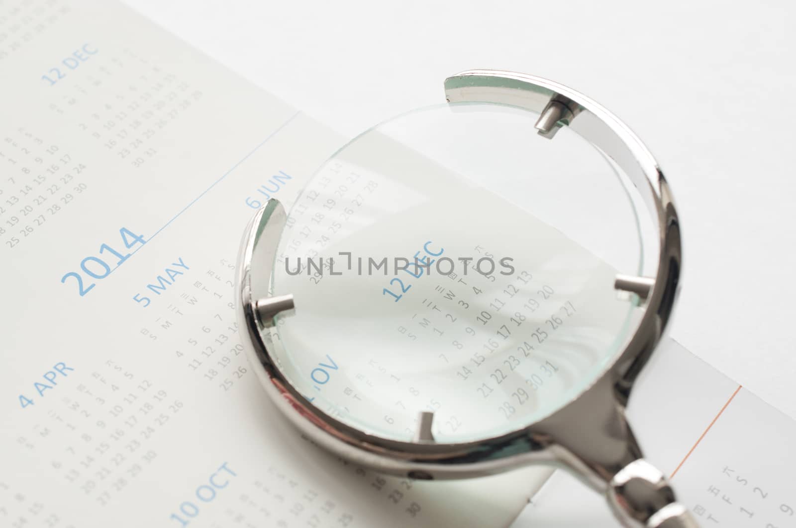 Hand holding magnifying glass to checking calendar of December