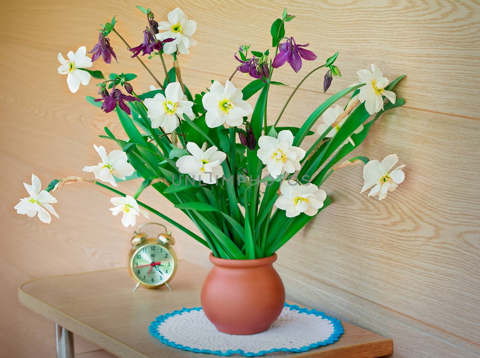 Blossoming narcissuses in a vase on a table. by georgina198