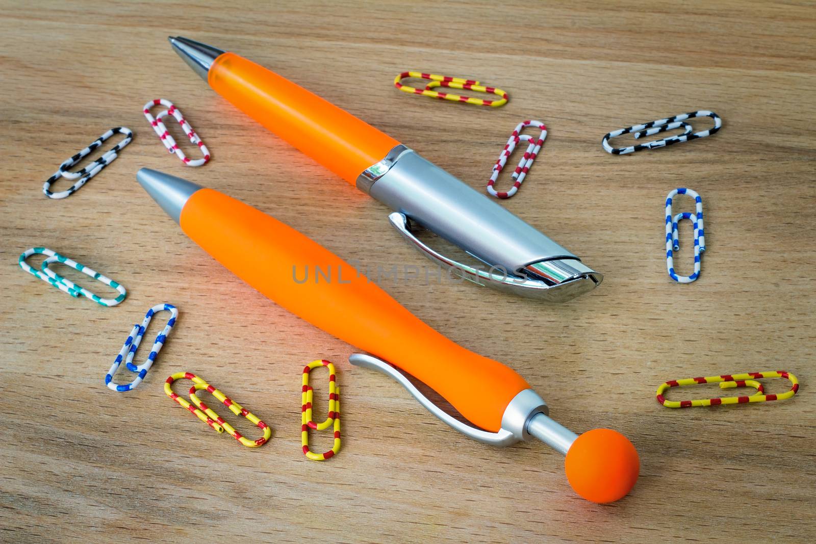 
Two handles of bright orange color for the letter and multi-colored paper clips for documents. Are located on a table