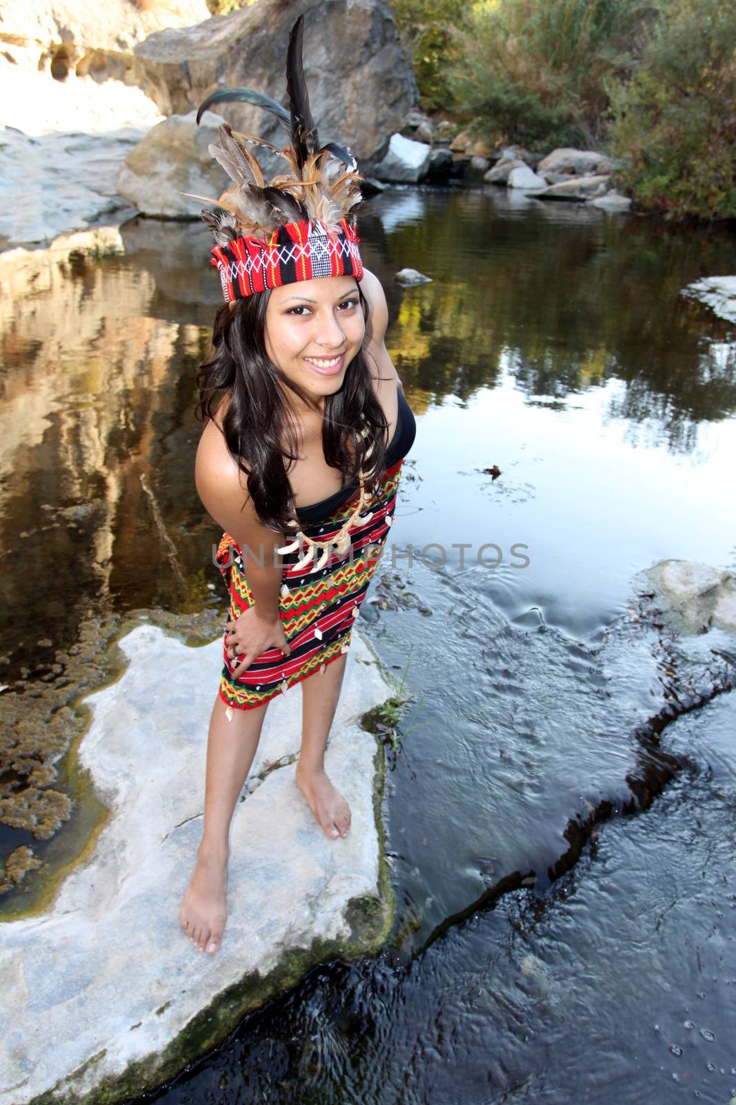 Native american woman next to a creek.