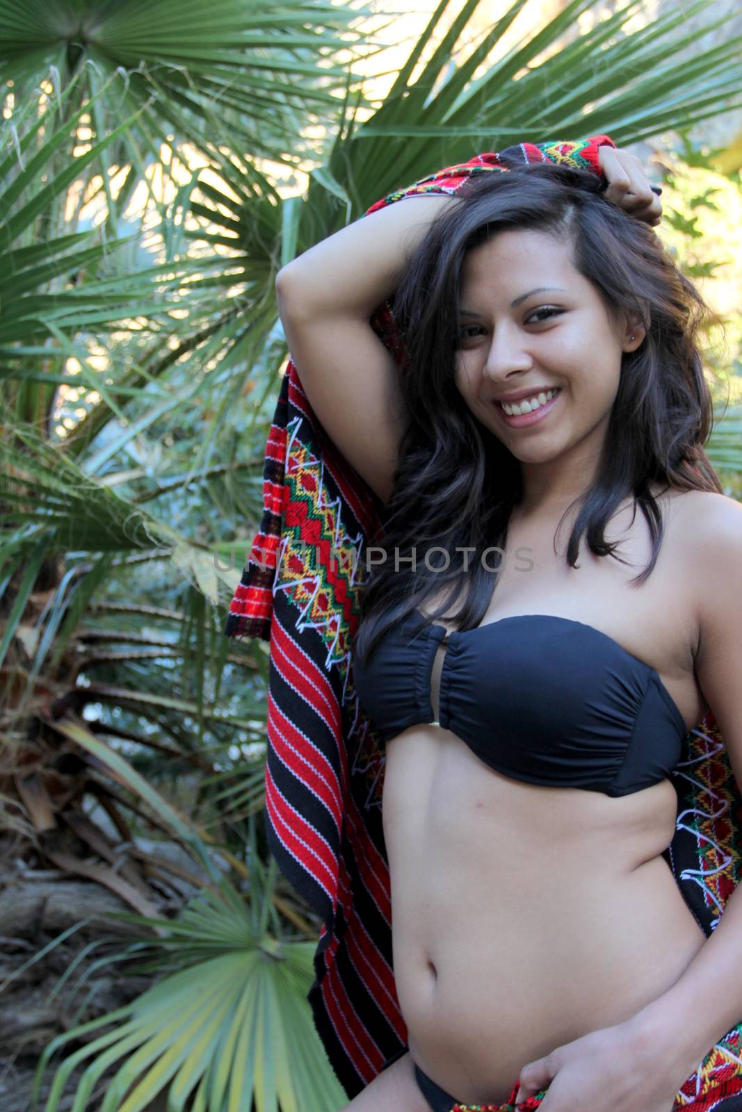 Model shot of a Hispanic beauty in front of a palm tree.
