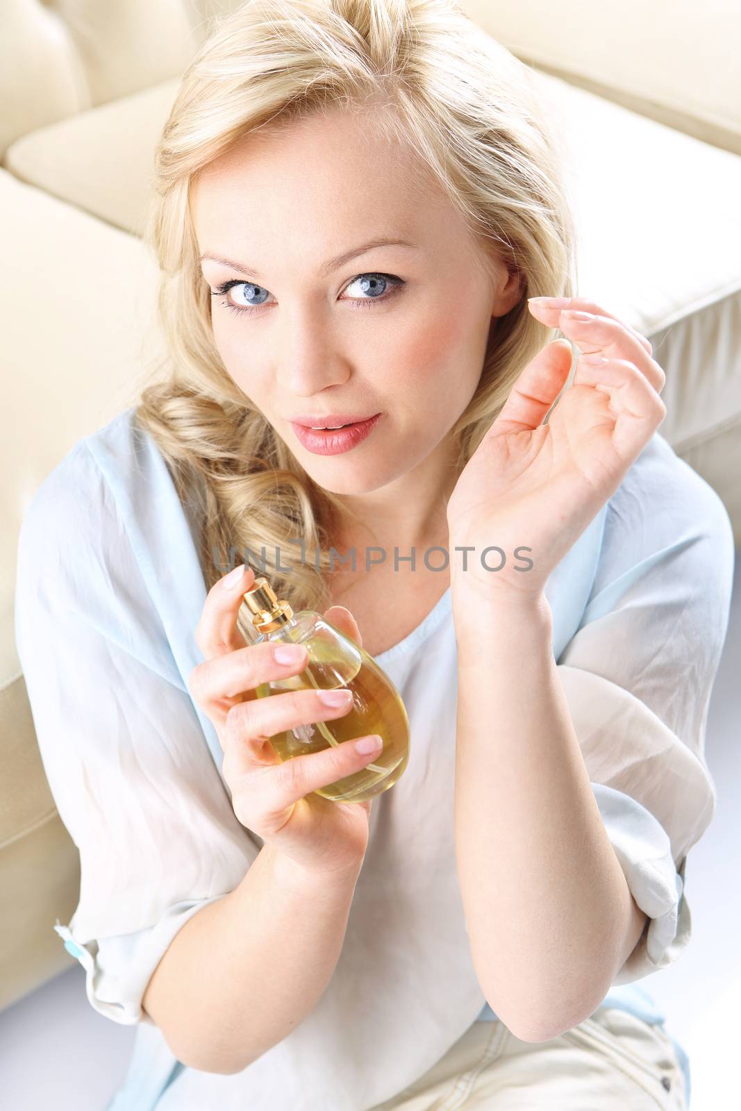 Form of a beautiful blonde holding in his hand a bottle of perfume