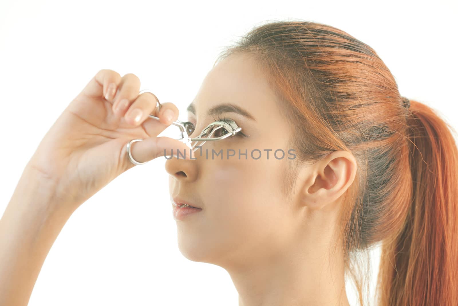 Young asian beautiful girl making her eyelashes wider with curler