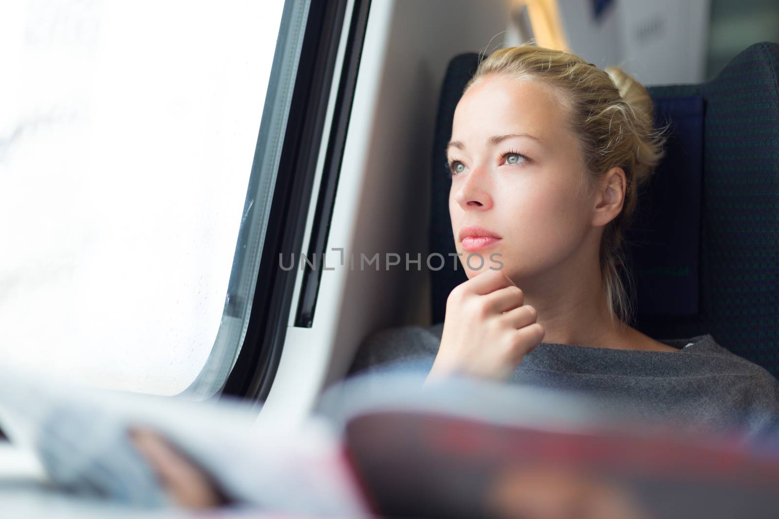 Thoughtful young lady reading while traveling by train.