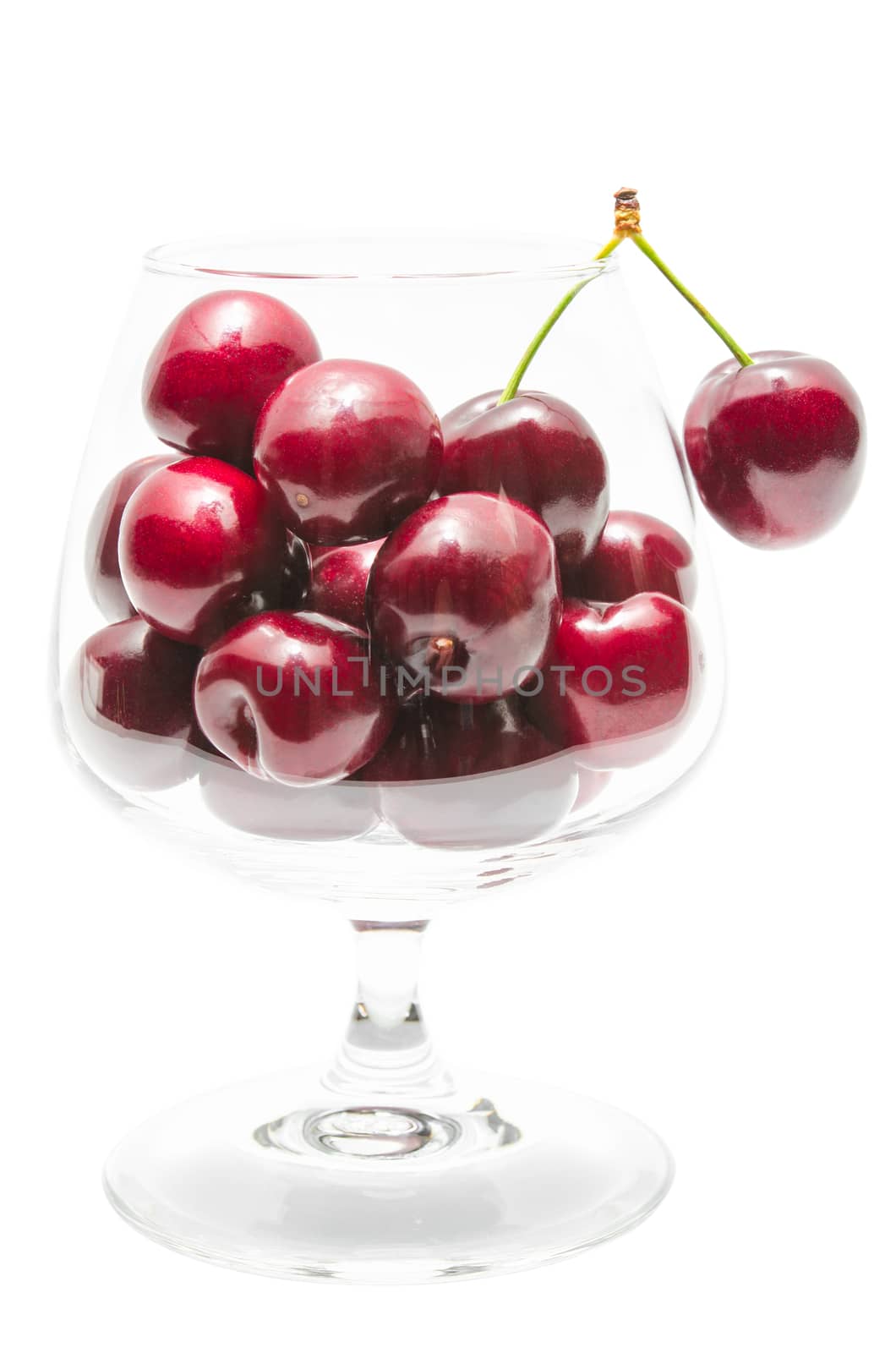 Ripe cherry big berries in transparent clear wineglass isolated on white
