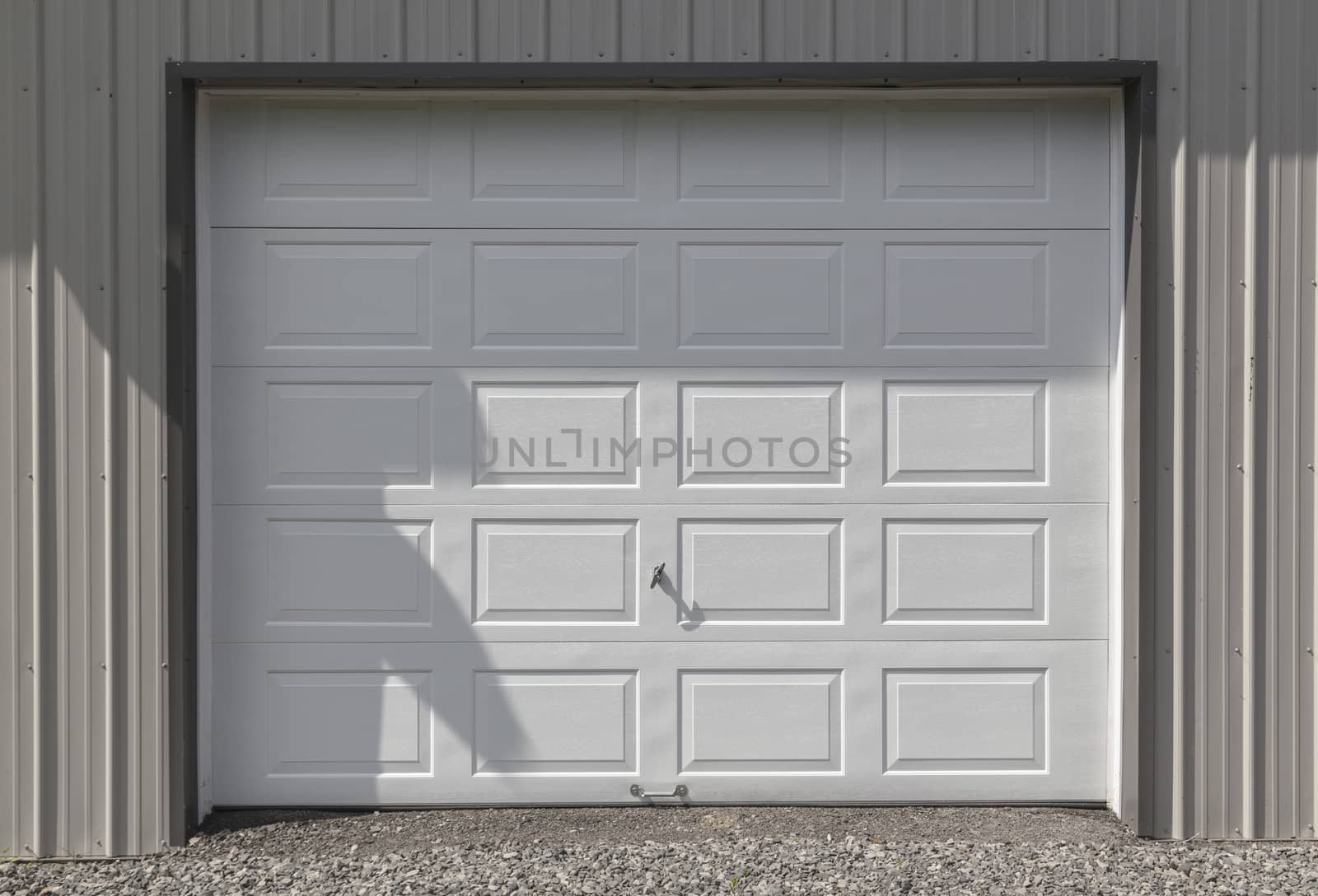 Clean and crisp white metal garage or barn door. The siding is light grey. 