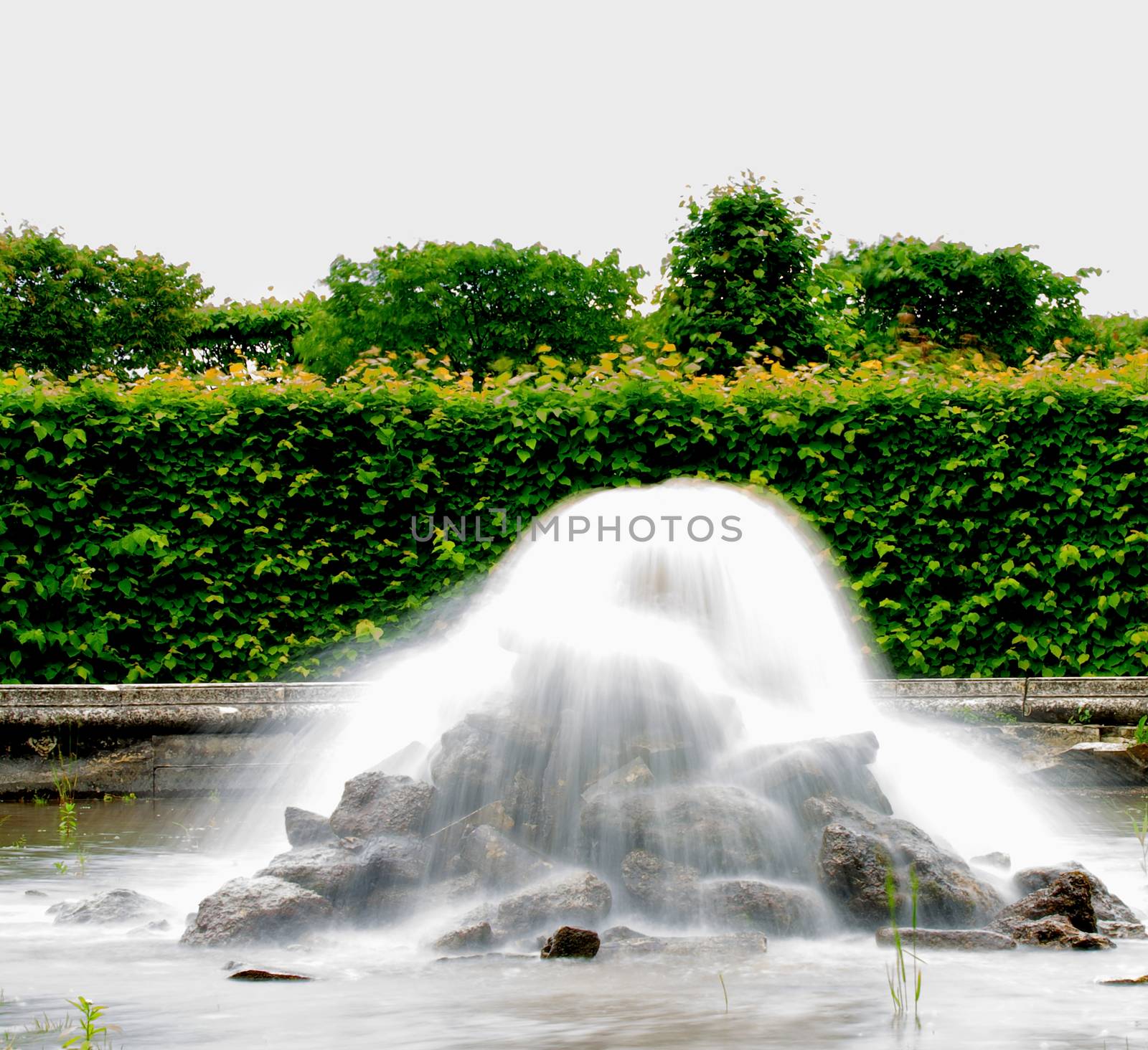 Decorative Fountain with Flowing Softly Water between Formal Garden Outdoors
