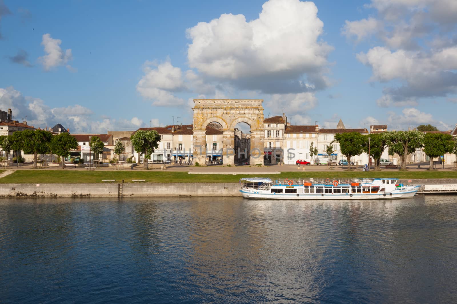 Panoramic view from the city of Saintes in the french region of Charente with the charente river, the city quay,a touristic boat and the roman germanicus arch