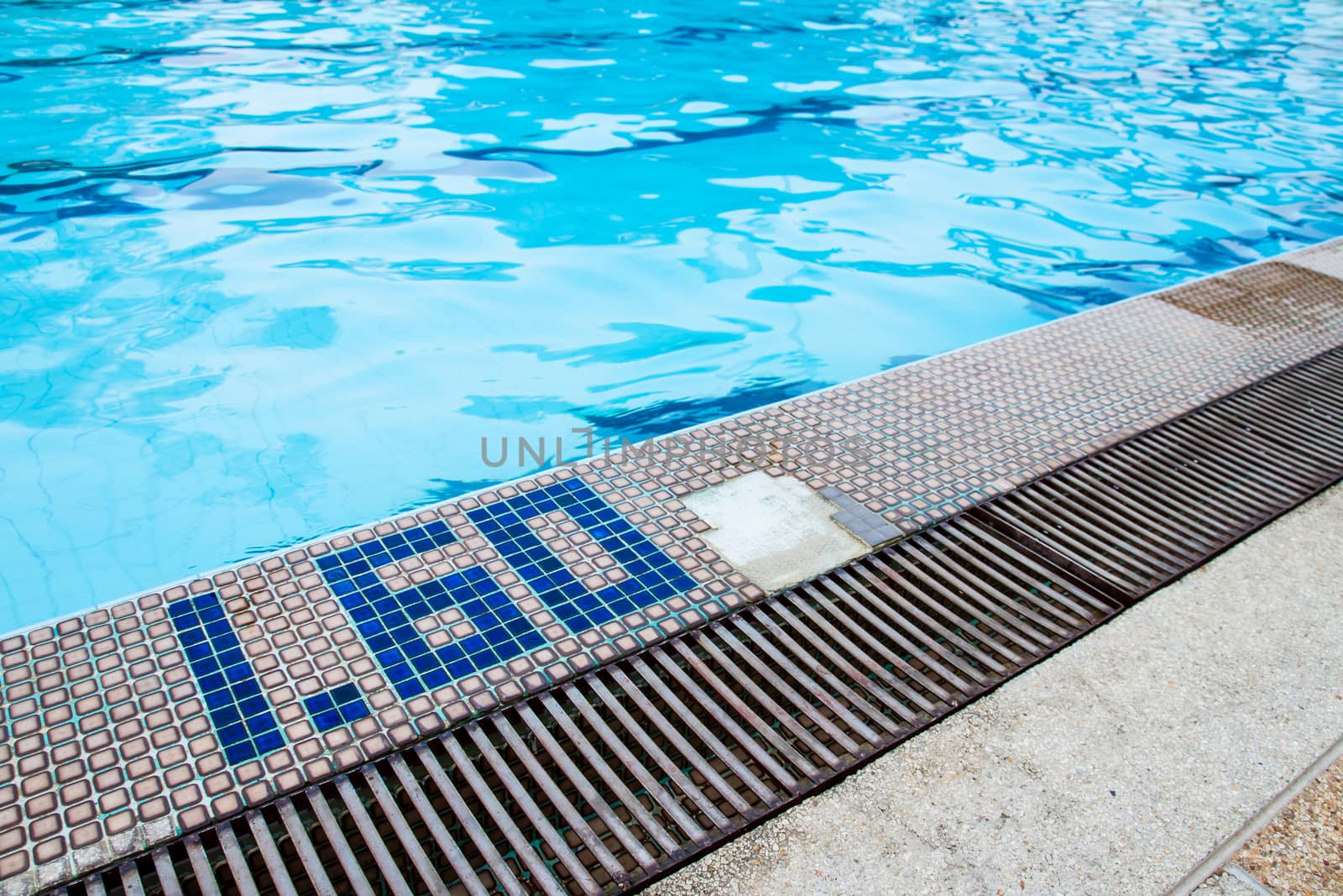 Swimming pool side with drain and cracked tiles