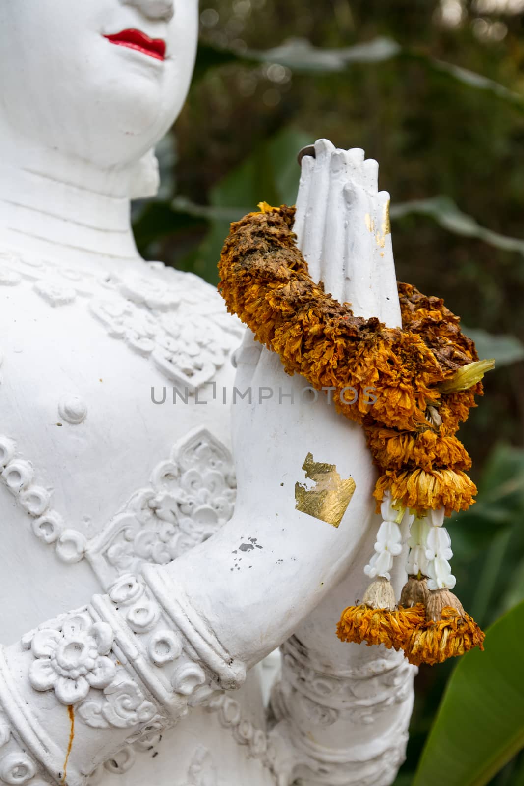 Praying hands of an antique statue with wreath around hands