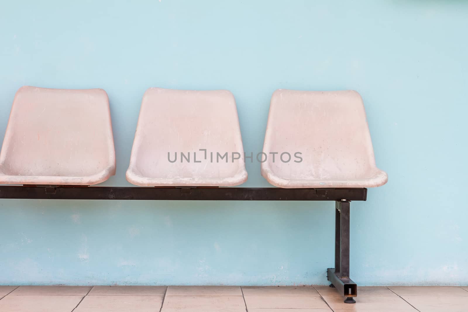 Old row of chairs with plain light blue wall