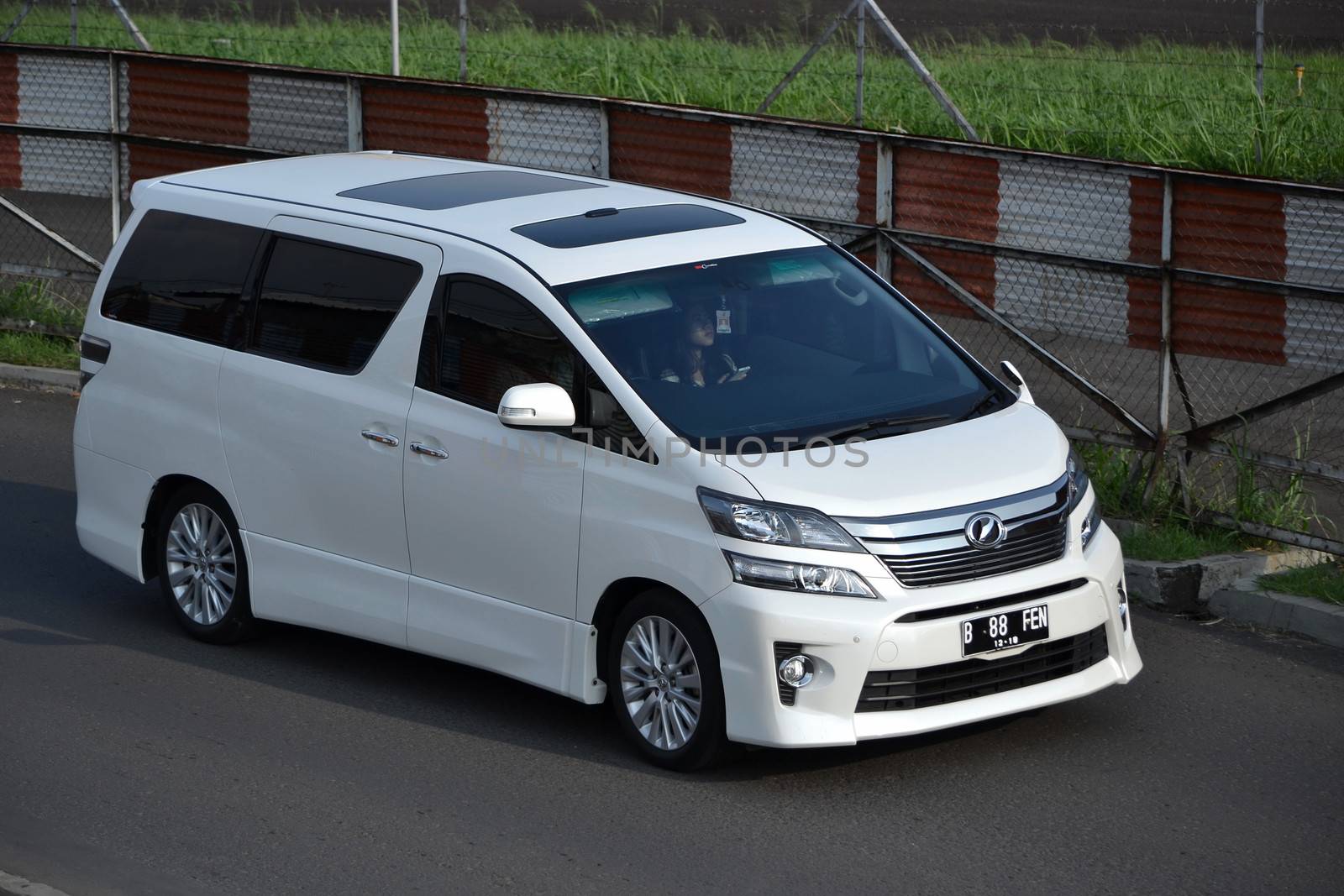bandung, indonesia-june 16, 2014: white colored toyota vellfire cruising on the road.