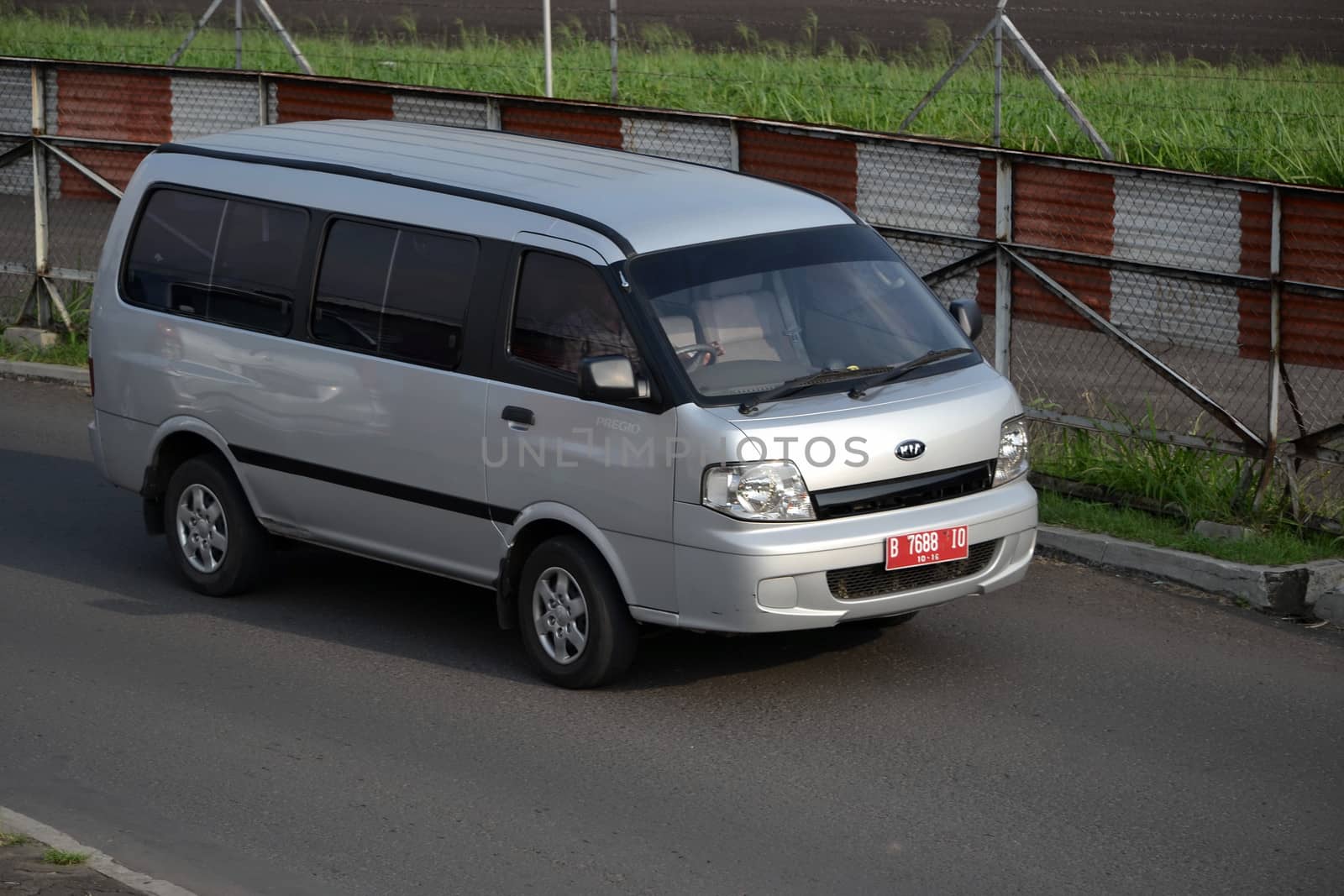 bandung, indonesia-june 16, 2014: silver colored KIA travello cruising on the road.