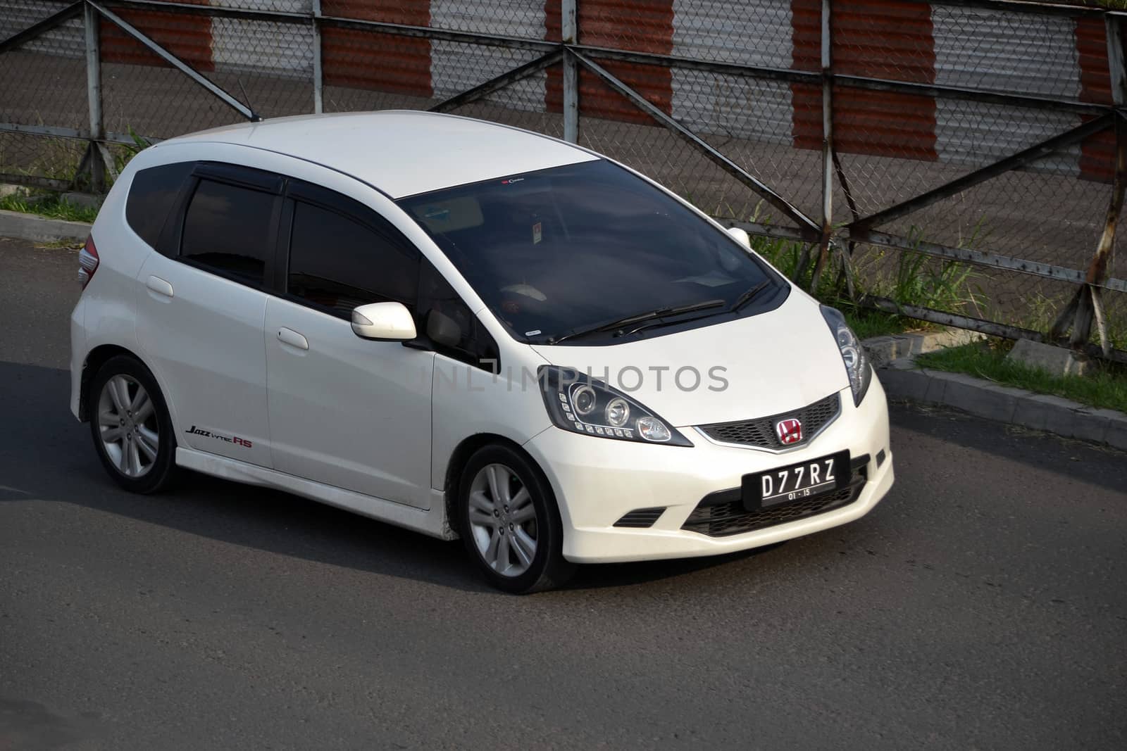 bandung, indonesia-june 16, 2014: white colored honda jazz RS cruising on the road.