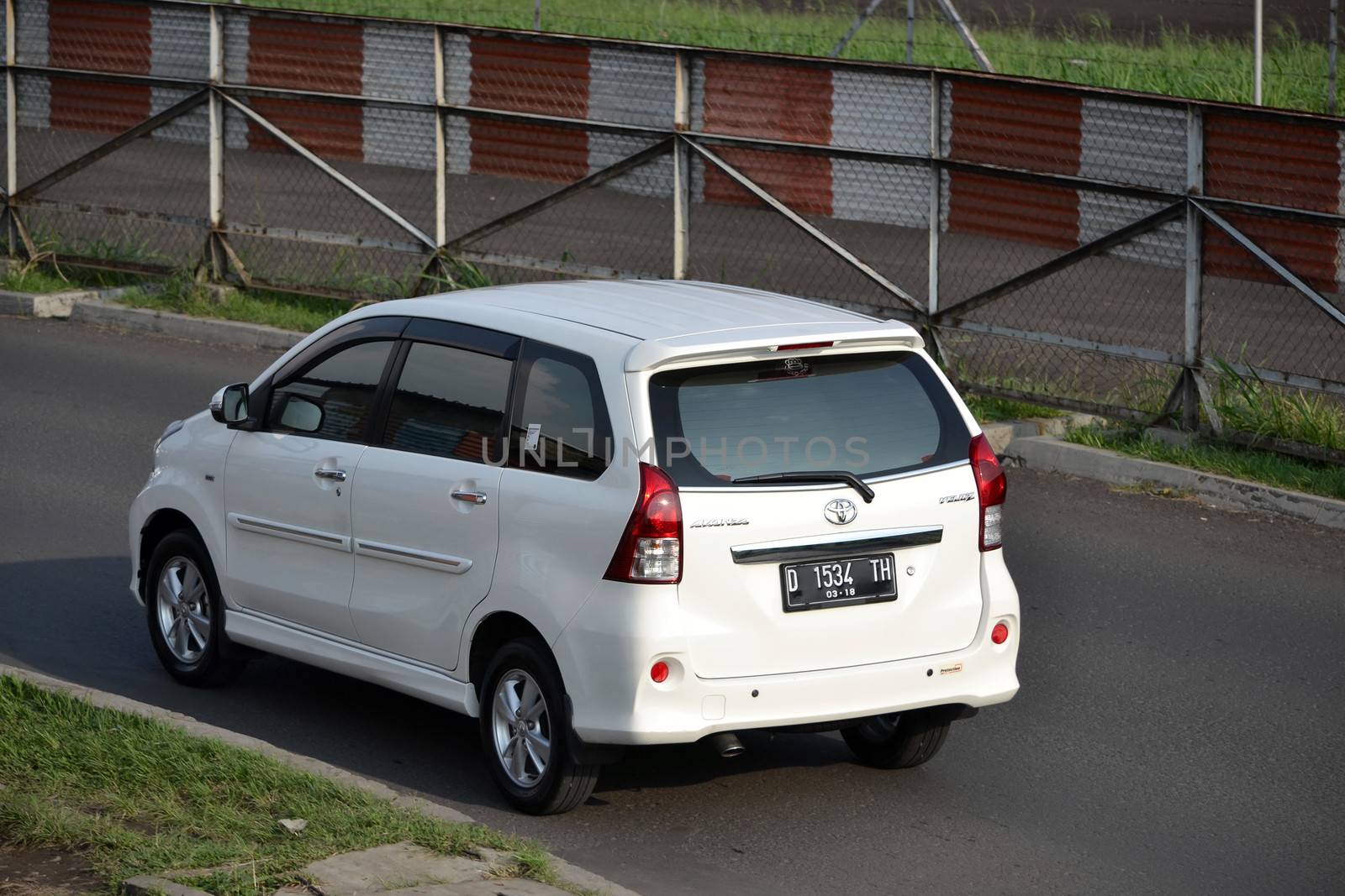bandung, indonesia-june 16, 2014: white colored toyota avanza cruising on the road.