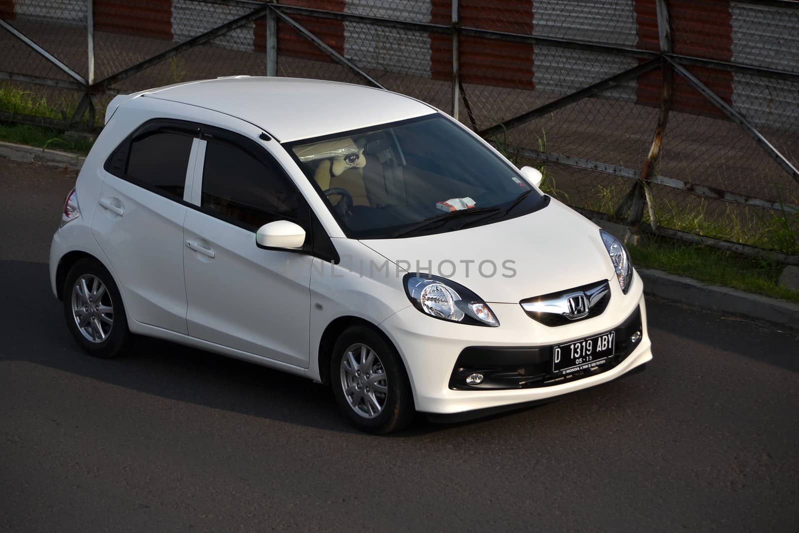 bandung, indonesia-june 16, 2014: white colored honda brio cruising on the road.