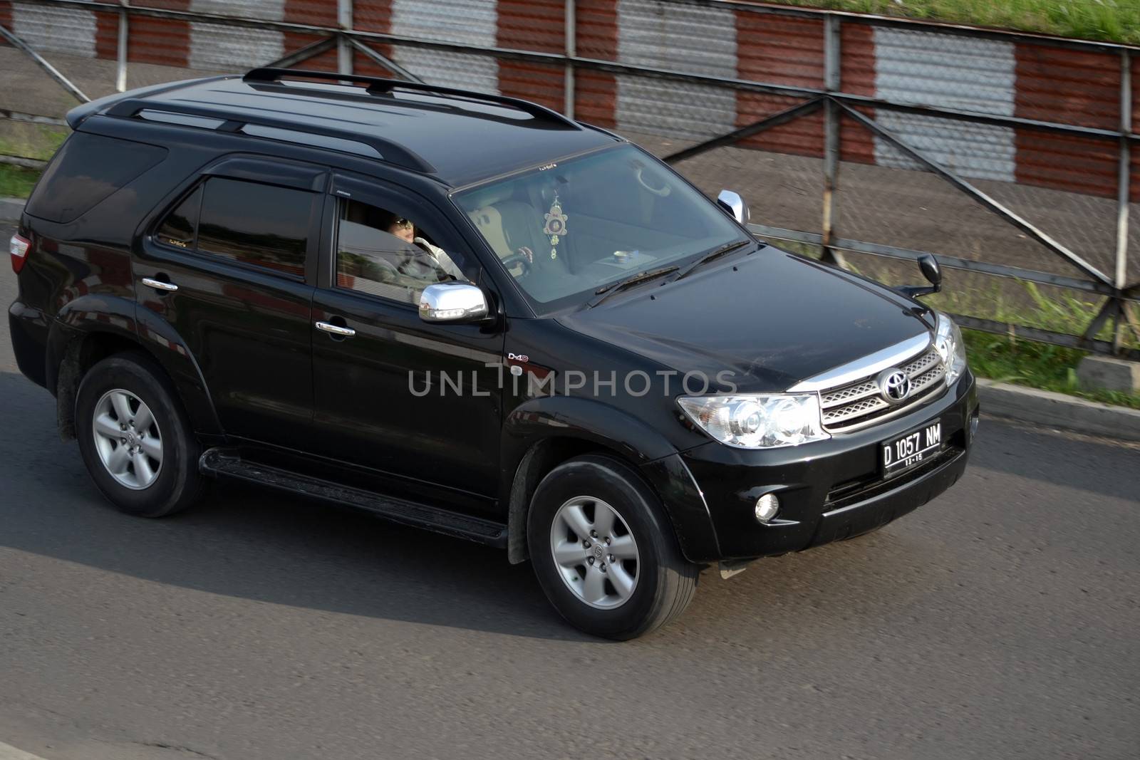 bandung, indonesia-june 16, 2014: black colored toyota fortuner cruising on the road.