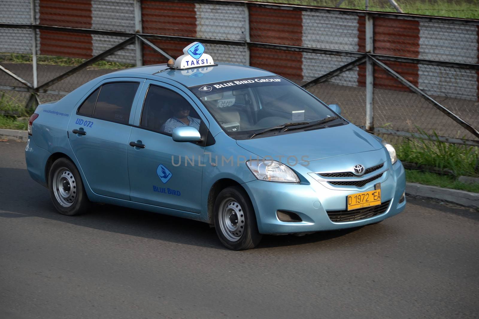 bandung, indonesia-june 16, 2014: blue bird taxi cruising on the road.