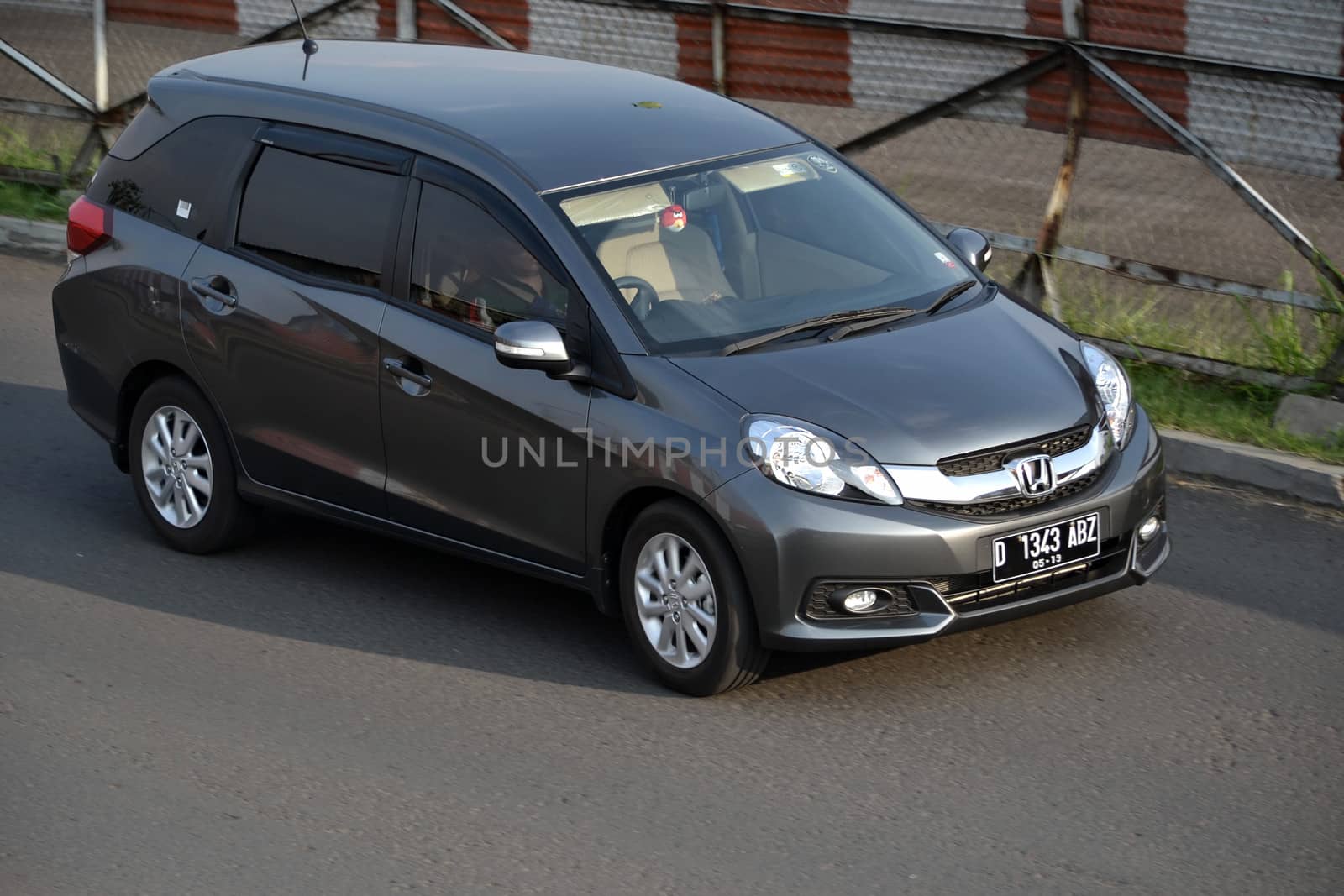 bandung, indonesia-june 16, 2014: grey colored honda mobilio cruising on the road.