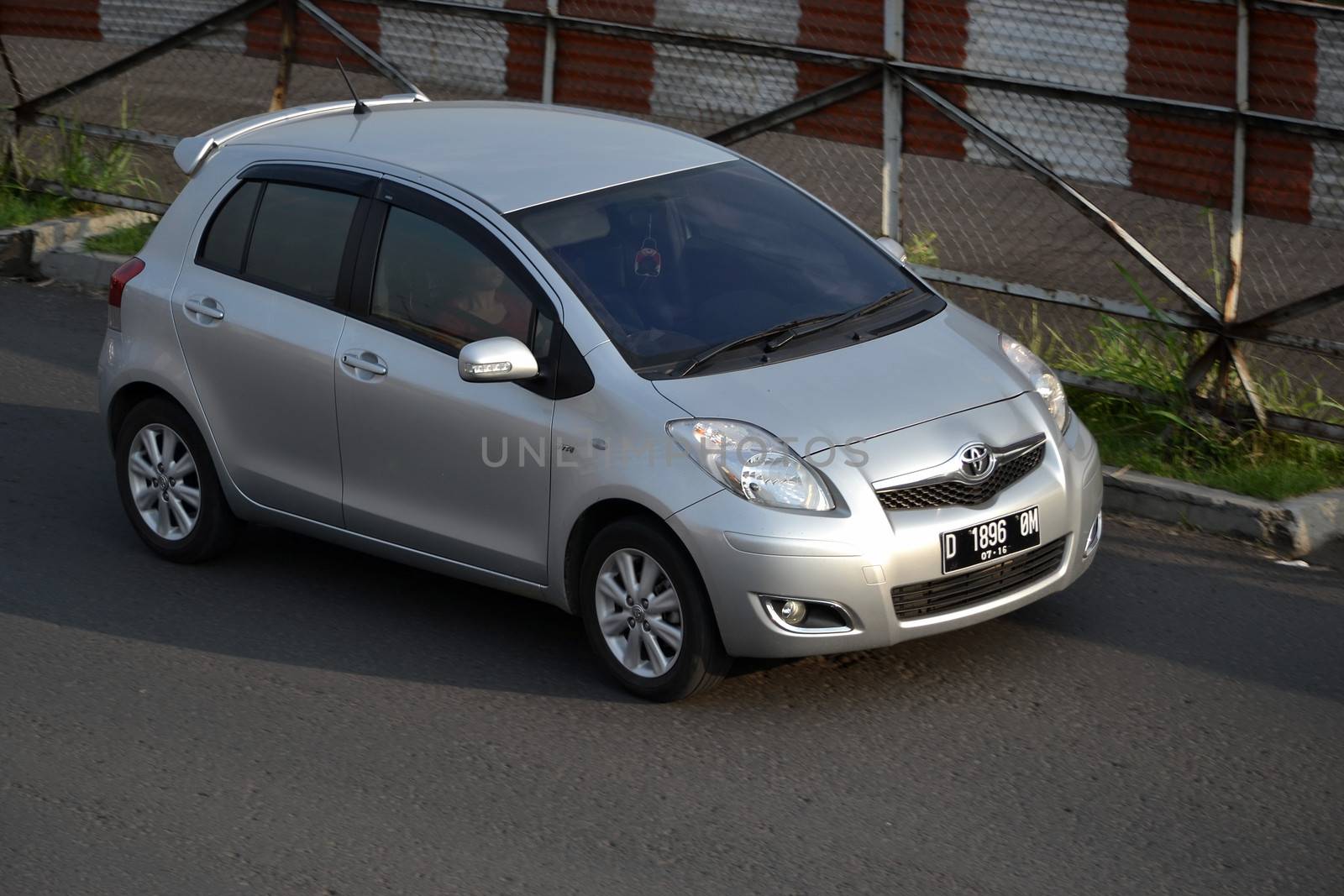 bandung, indonesia-june 16, 2014: silver colored toyota yaris cruising on the road.