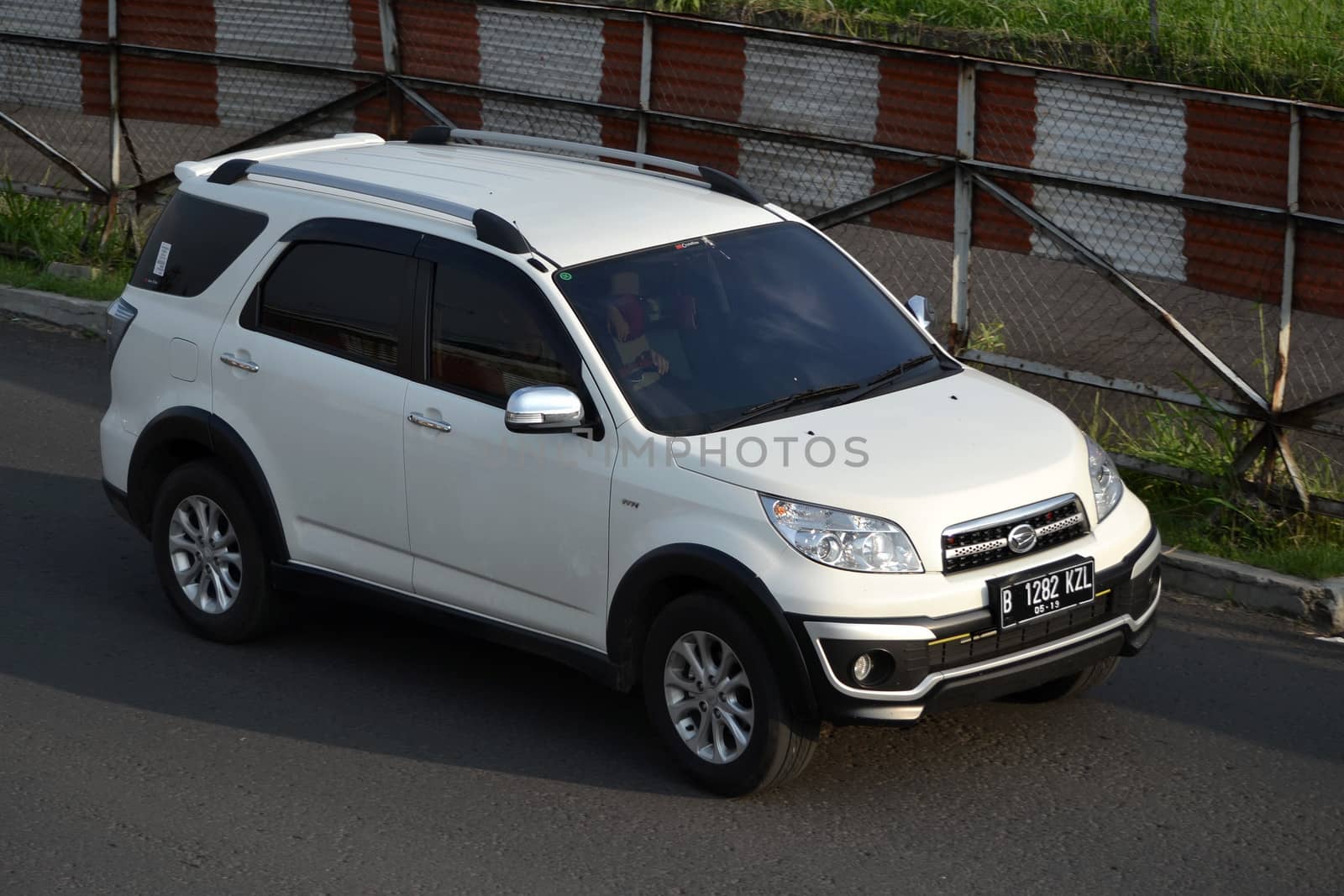 bandung, indonesia-june 16, 2014: white colored daihatsu terios cruising on the road.