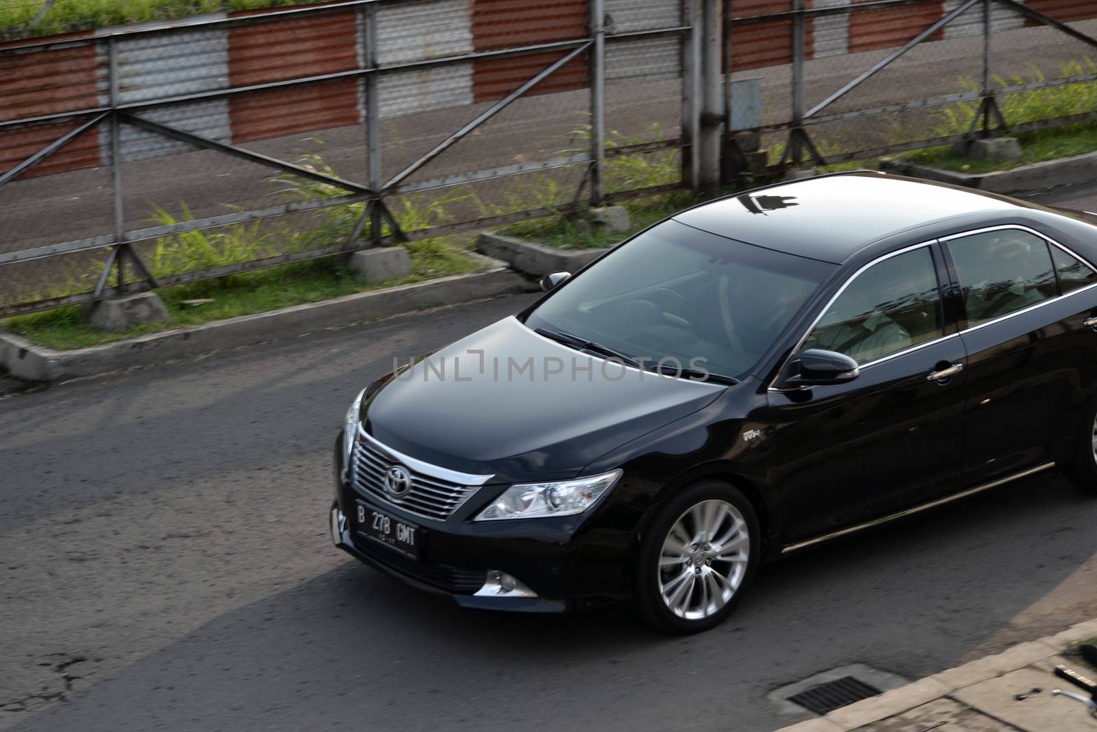 bandung, indonesia-june 16, 2014: black colored toyota camry cruising on the road.