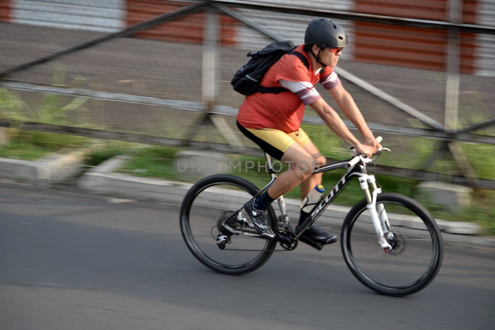 bandung, indonesia-june 16, 2014: man with backpack are riding bicycle in the afternoon.