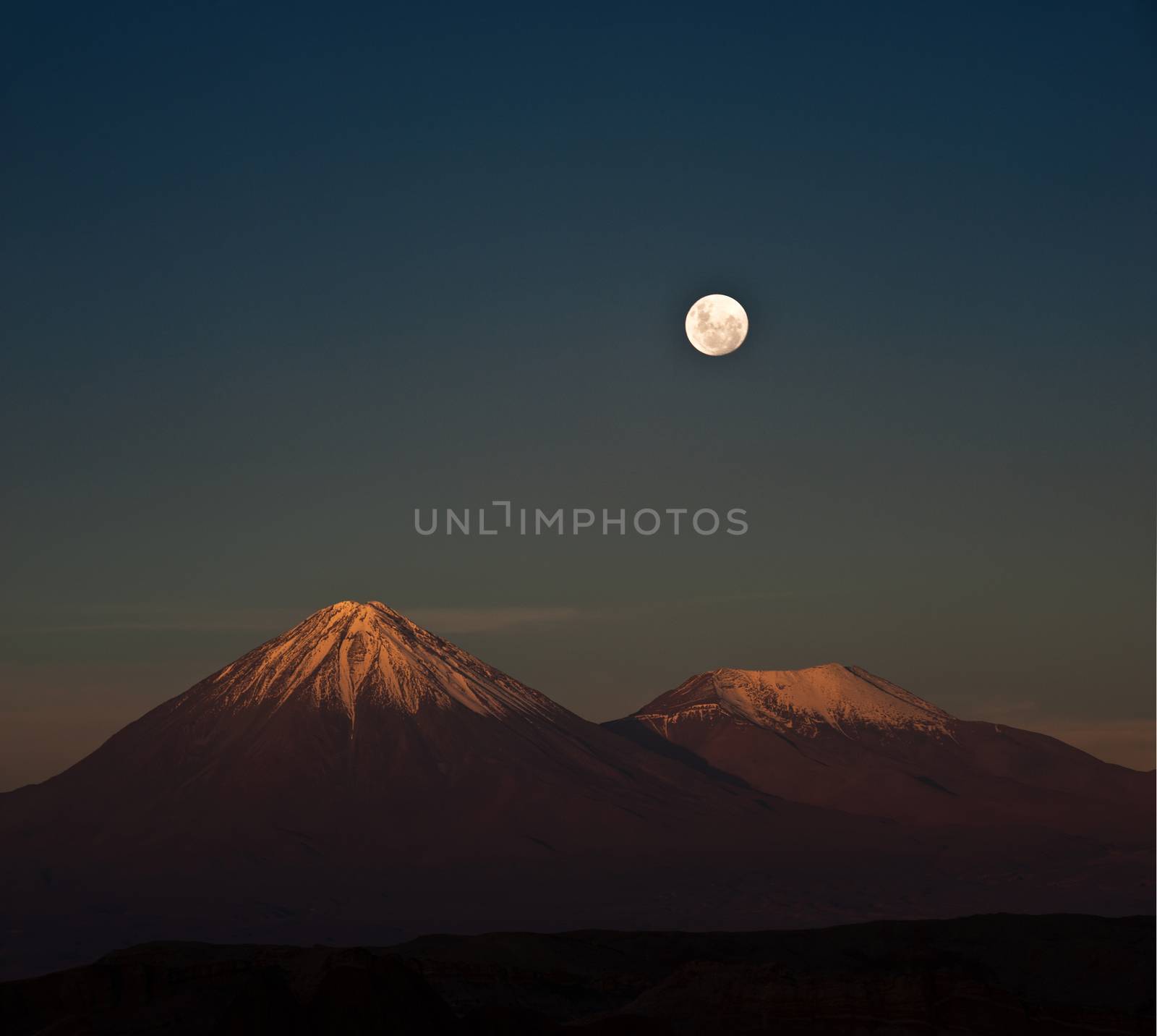 Full-moon in the Moon Valley. Volcanoes Licancabur and Juriques, west of San Pedro de Atacama, Chile in the Cordillera de la Sal, in the Atacama desert of Chile