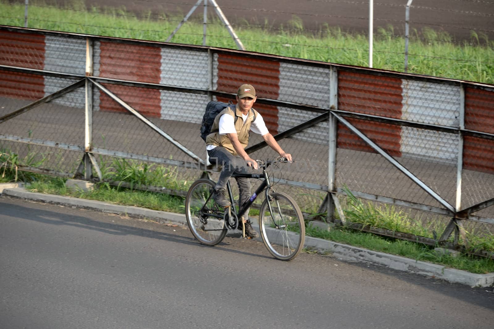 bandung, indonesia-june 16, 2014: man with backpack are riding bicycle in the afternoon.