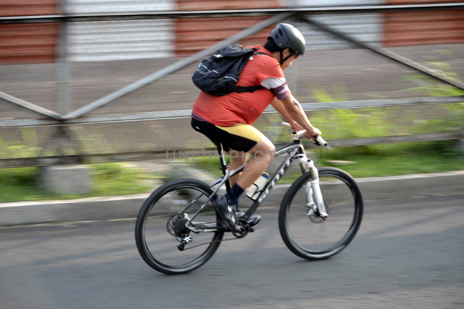bandung, indonesia-june 16, 2014: man with backpack are riding bicycle in the afternoon.