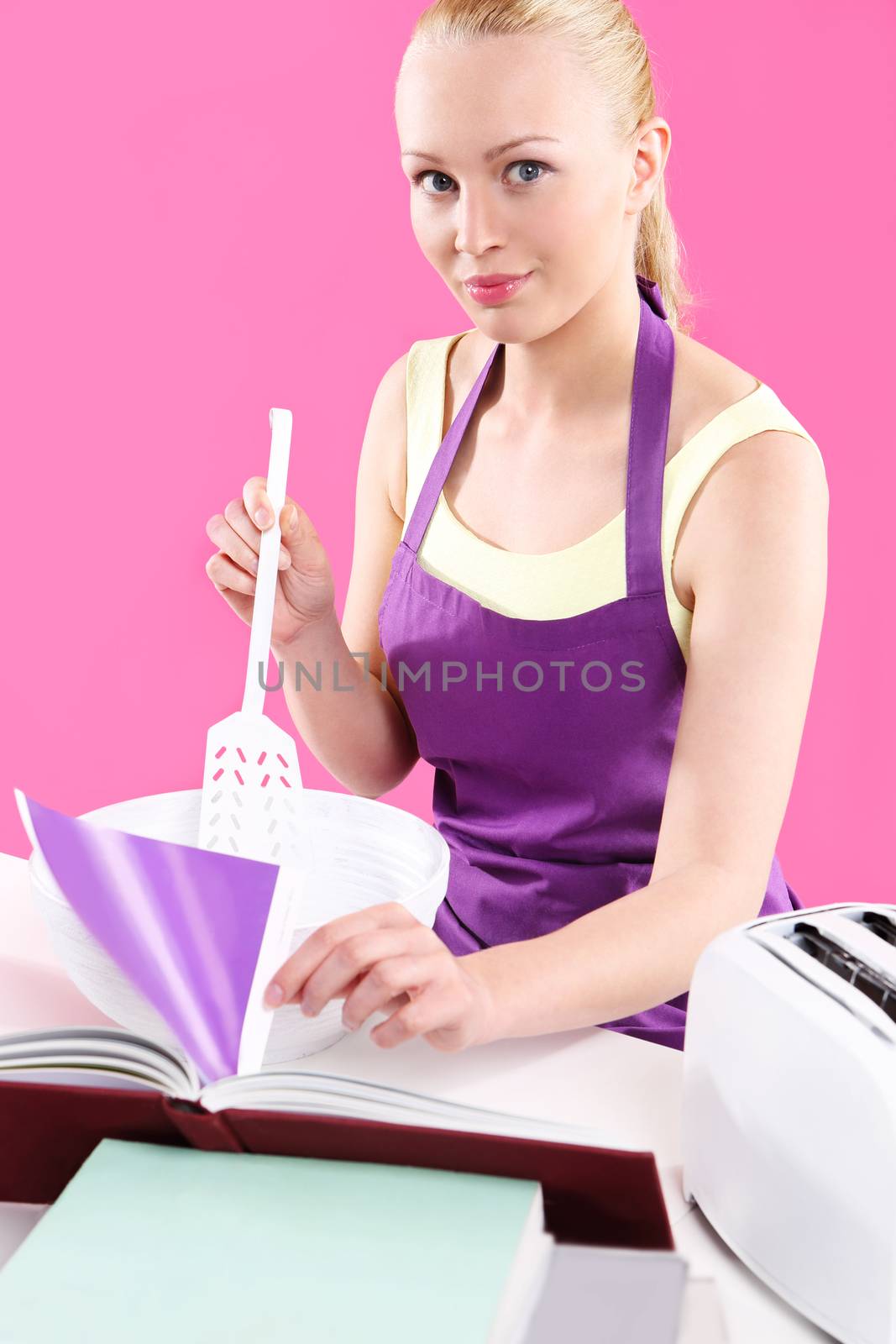 Young, attractive housewife cooks food in a pink kitchen