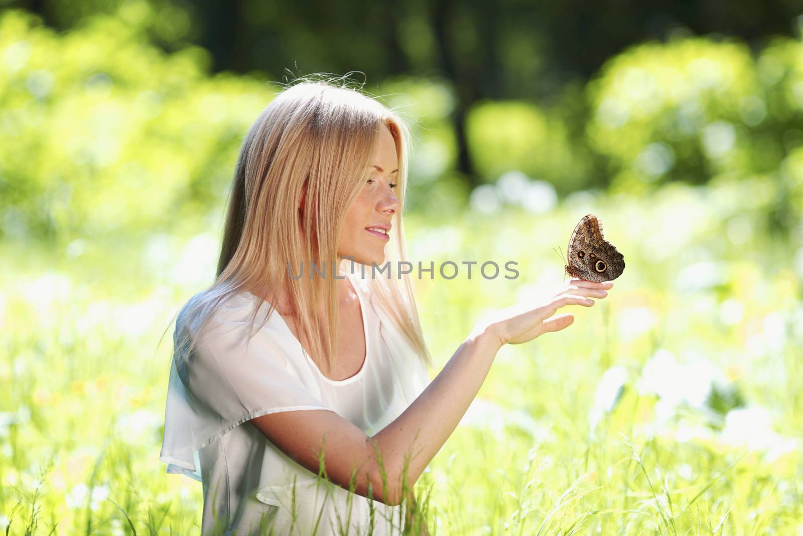 Beautiful young happy Woman playing with butterfly outdoors