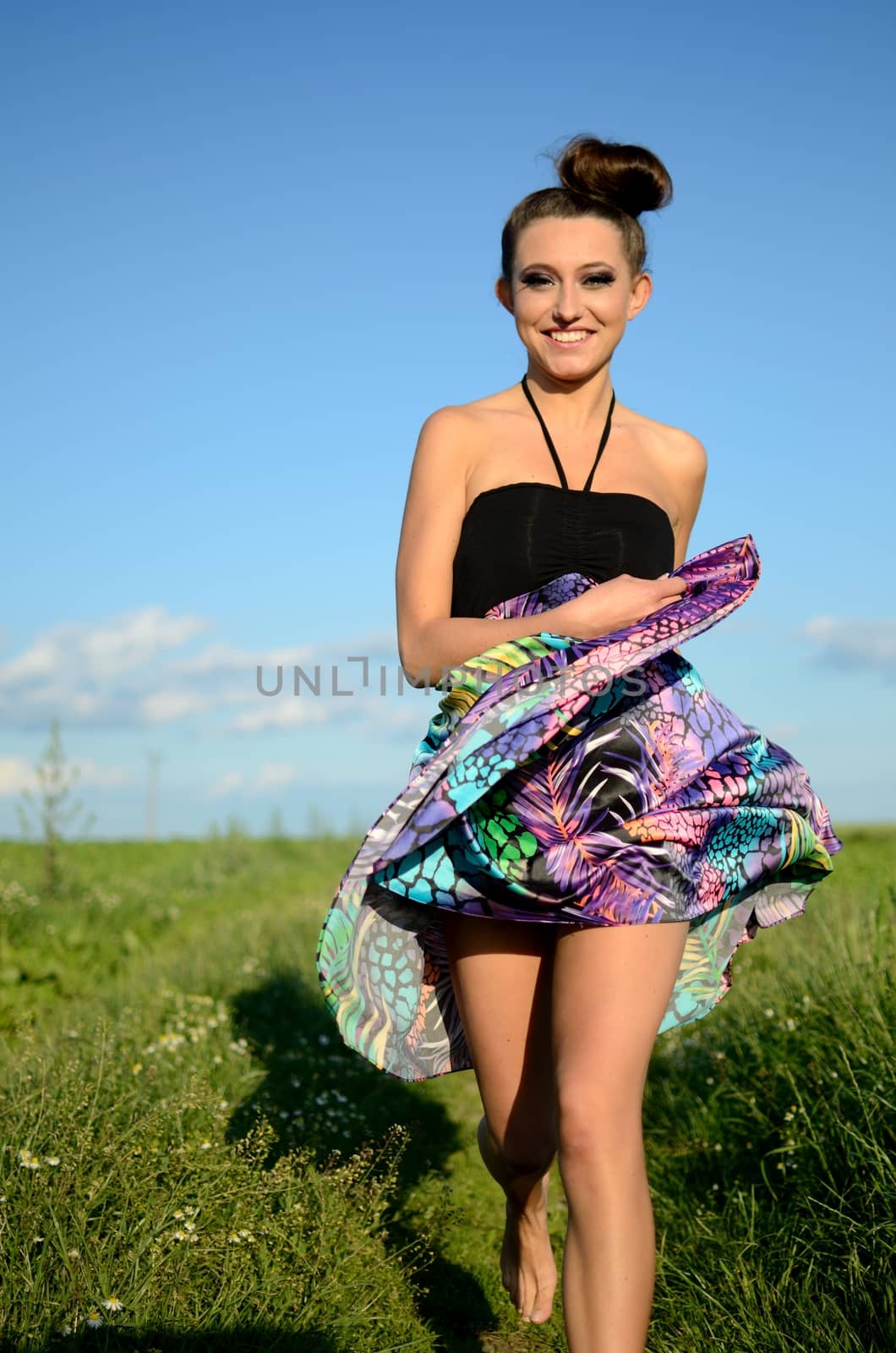 Young female model from Poland surrounded by green fields of grains. Girl portrait with colorful skirt.