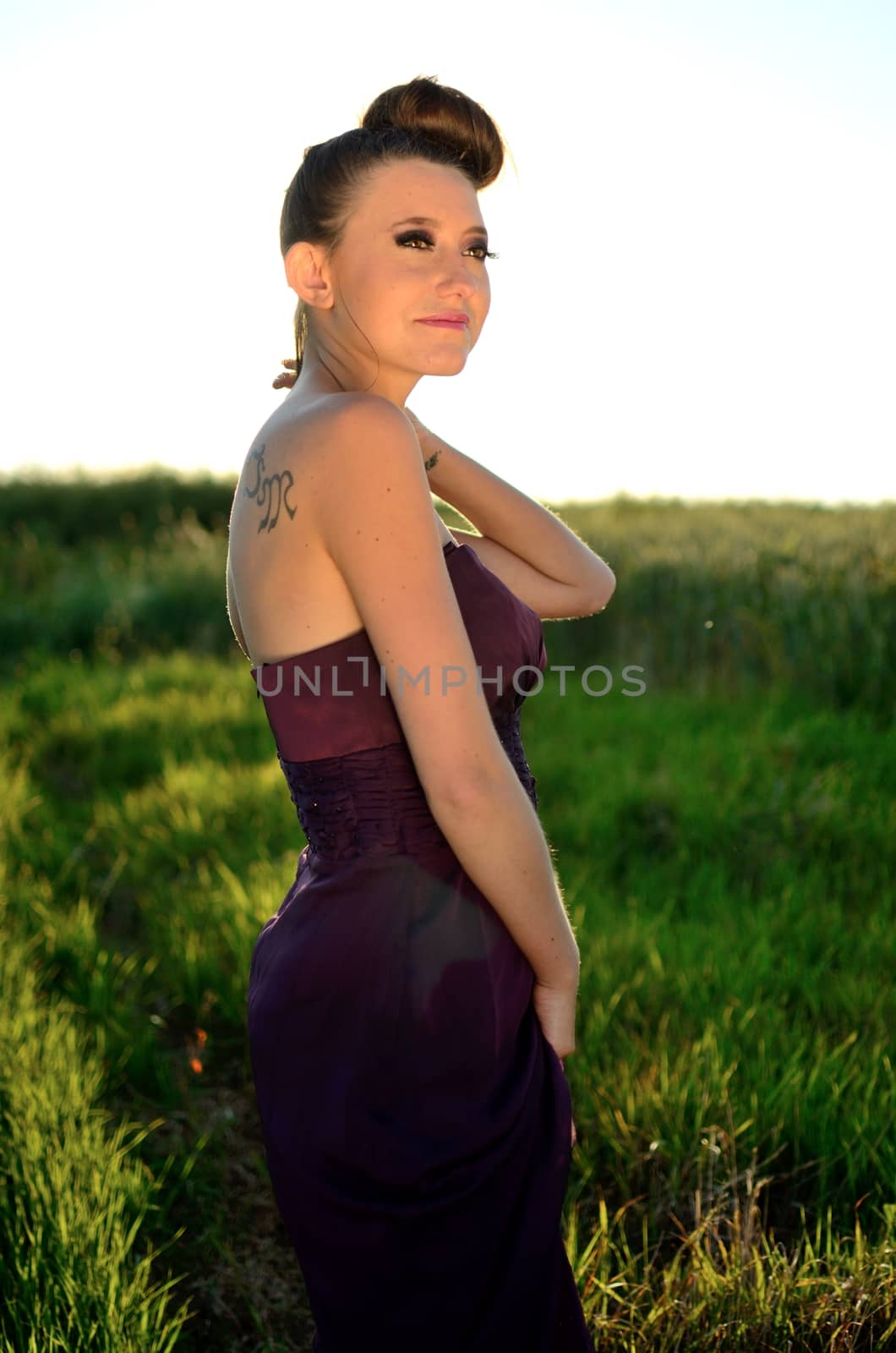 Female model outdoor portrait during sunset. Warm sunlight. Polish girl wearing dark red dress, smiling gently.