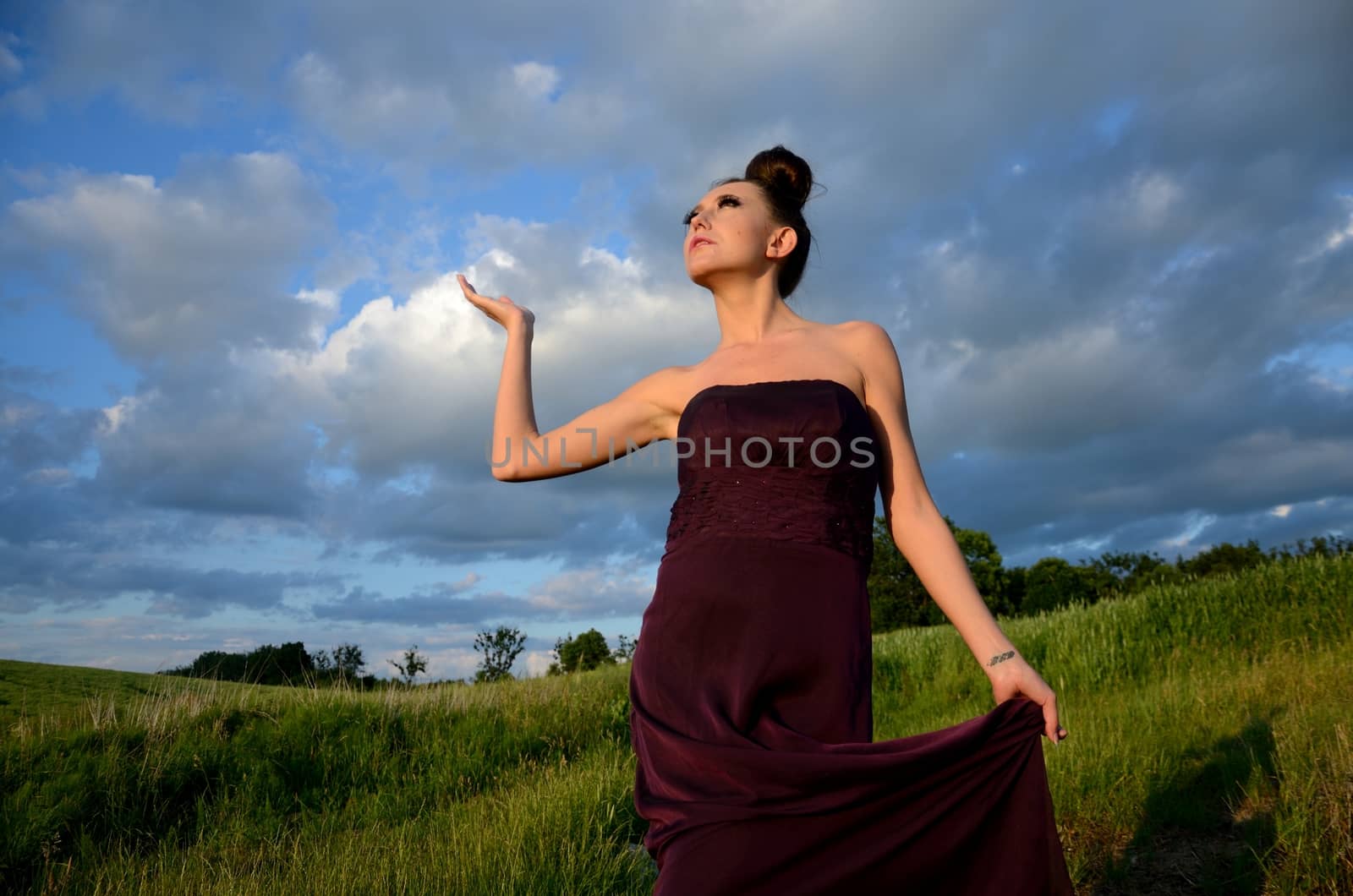 Beautiful girl from Poland, outdoor portrait. Young female model posing with different hands gesture. Blue sky with single clouds and green fields as background.