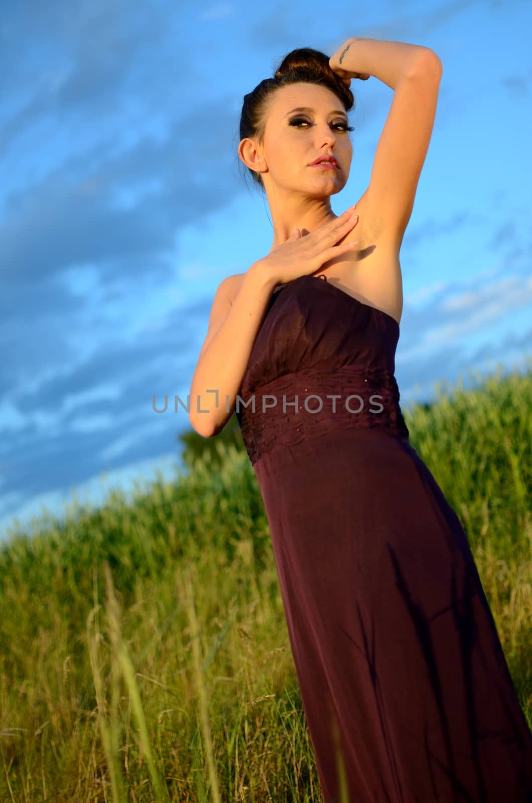 Beautiful girl from Poland, outdoor portrait. Young female model posing with different hands gesture. Blue sky with single clouds and green fields as background.