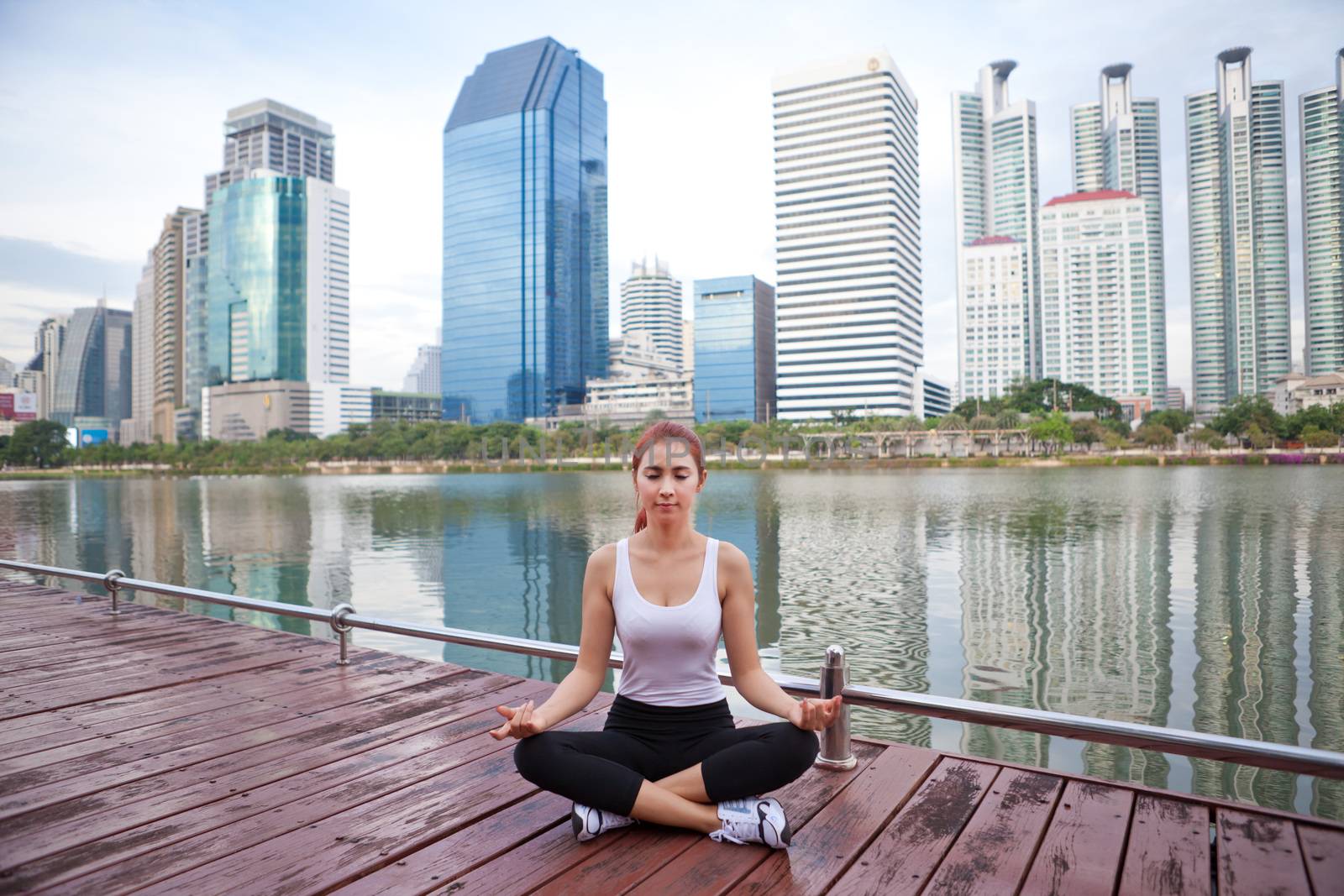 Young asian woman doing yoga exercises at the city park