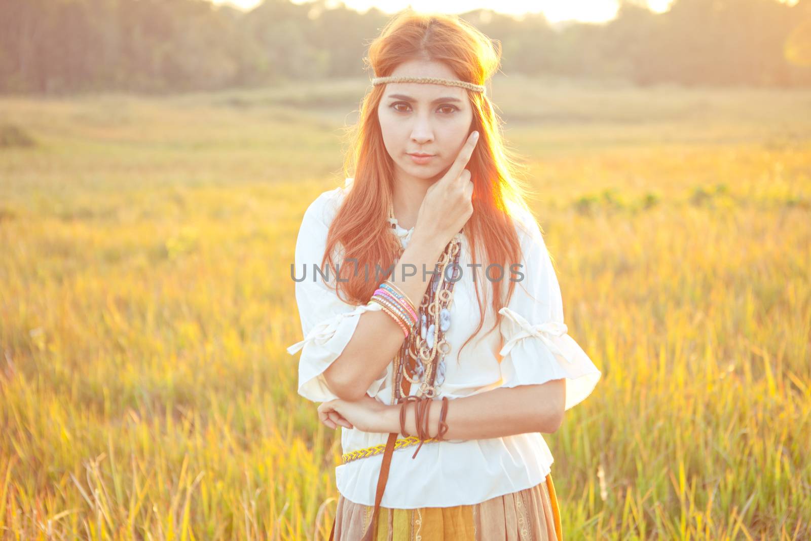 Hippie woman posing in golden field on sunset