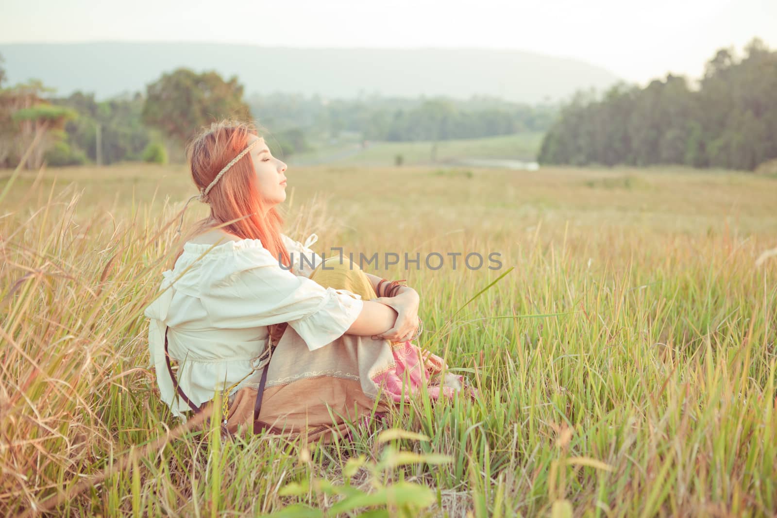 Country hippie girl sitting at golden field